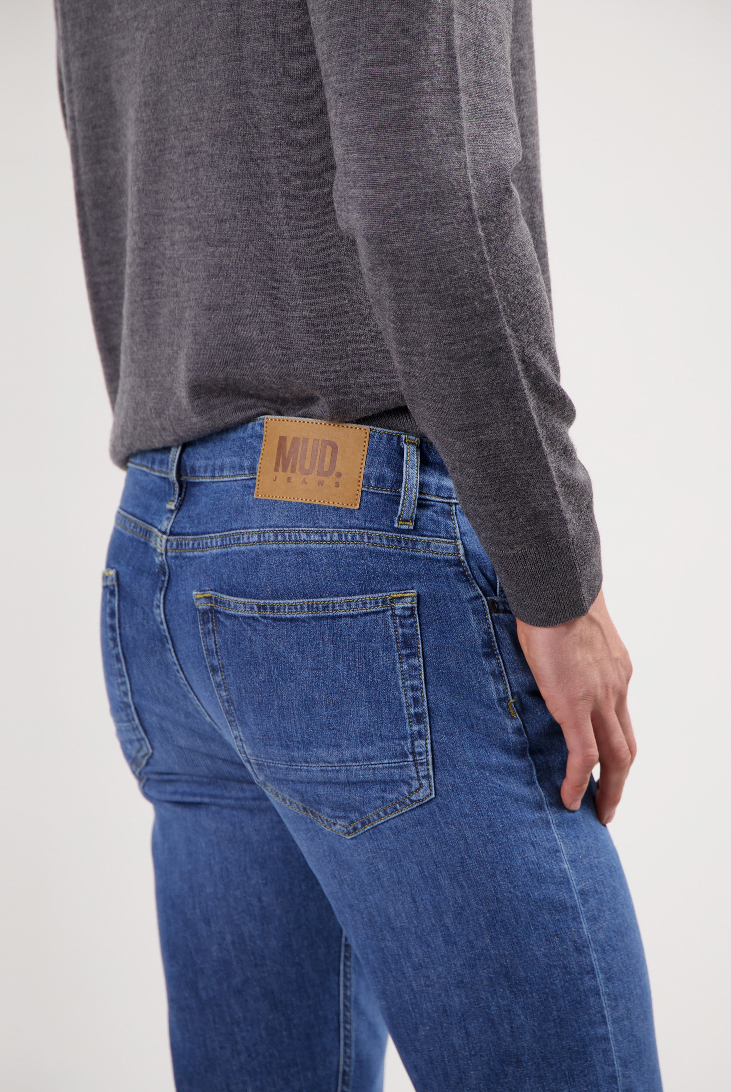 Sustainable MUD Jeans in slate blue with eco-friendly fabric, paired with a white T-shirt and sneakers.