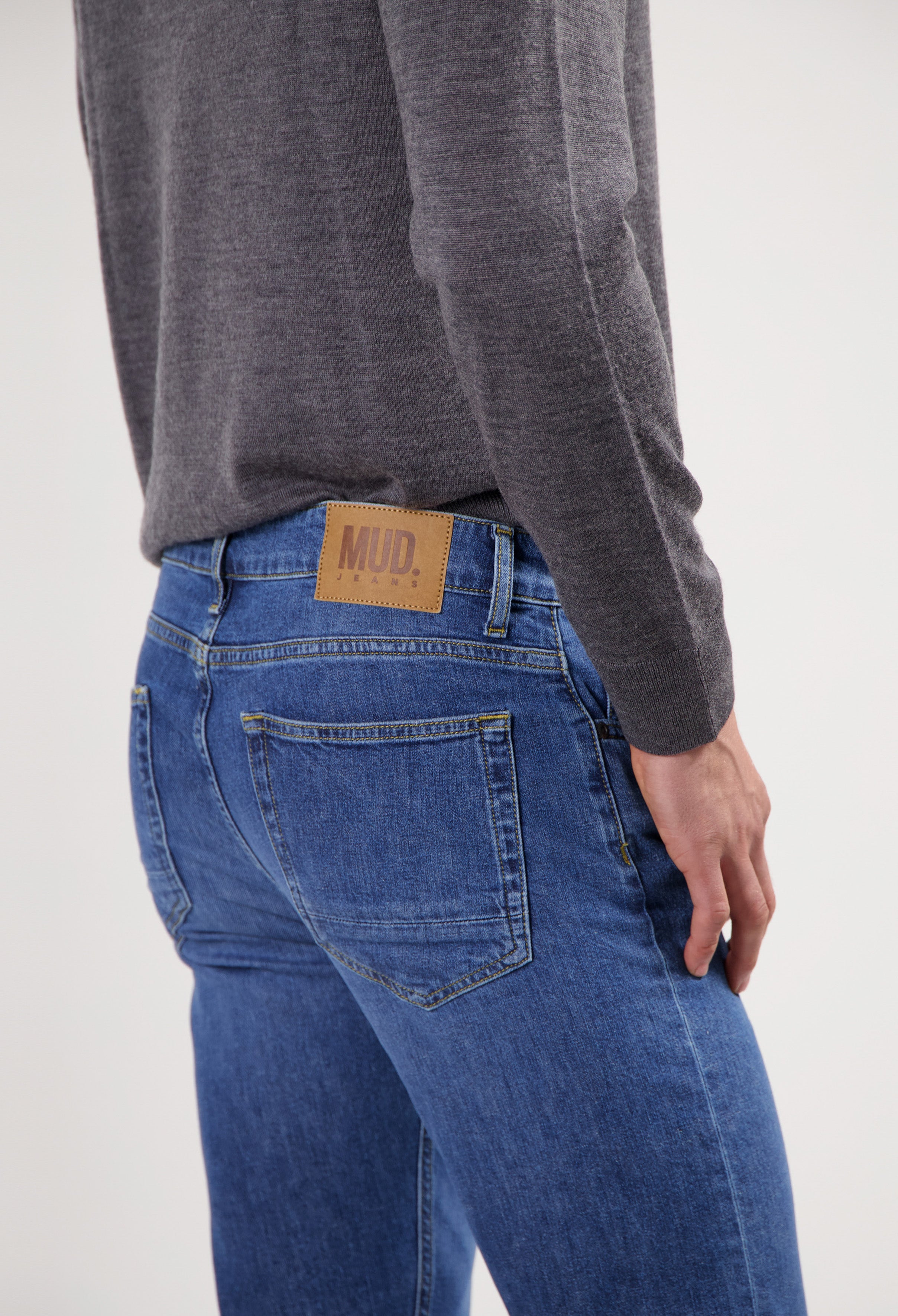 Sustainable MUD Jeans in slate blue with eco-friendly fabric, paired with a white T-shirt and sneakers.