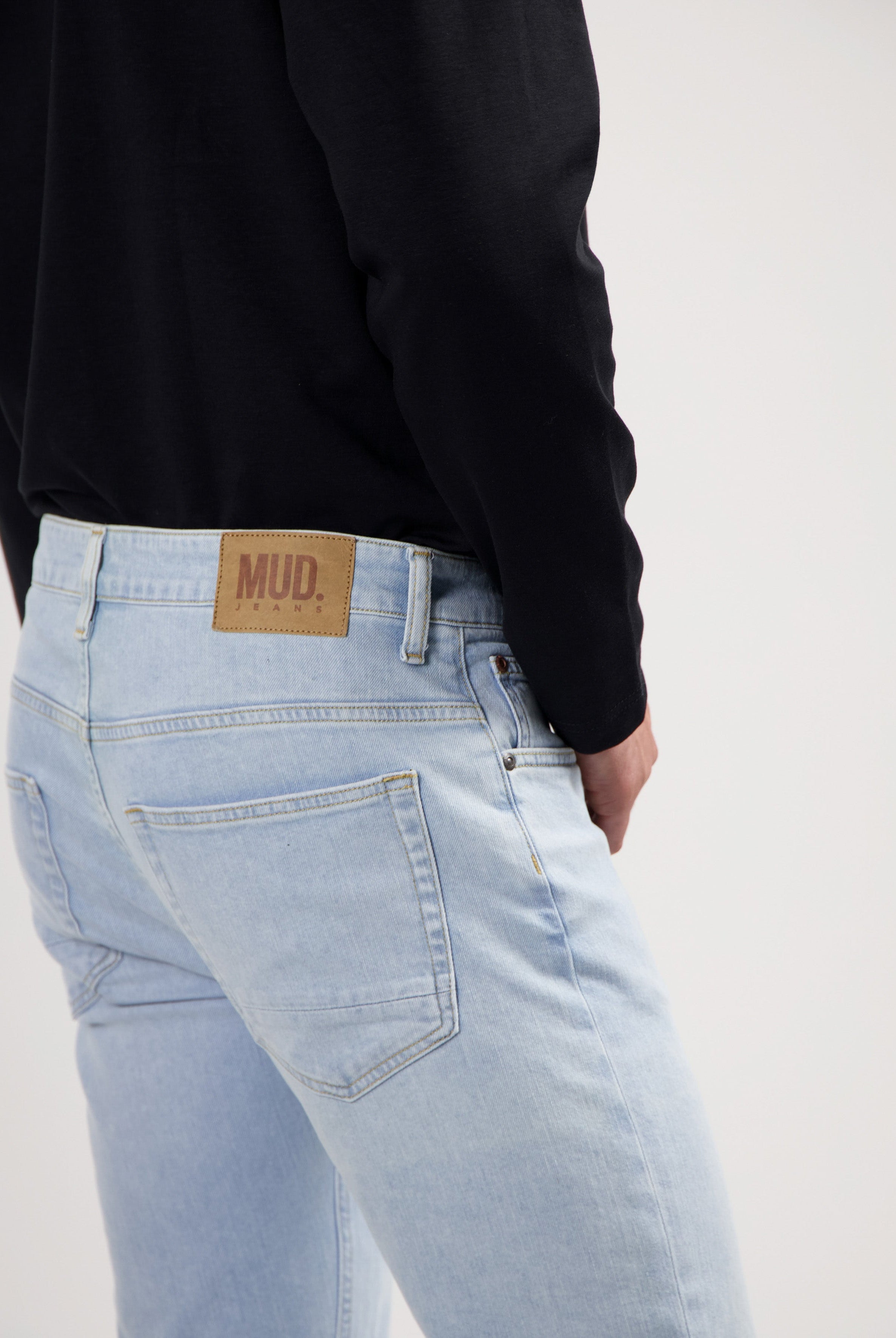 Sustainable MUD Jeans in gray denim, paired with a black sweater promoting eco-friendly fashion.