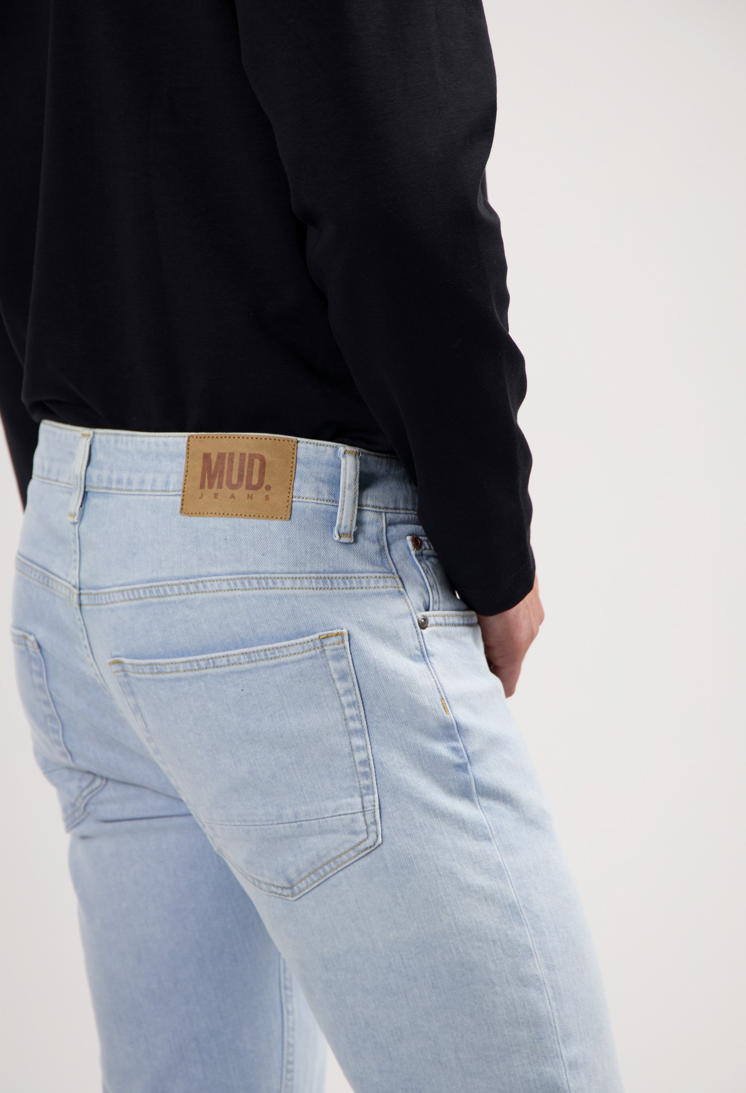 Sustainable MUD Jeans in gray denim, paired with a black sweater promoting eco-friendly fashion.