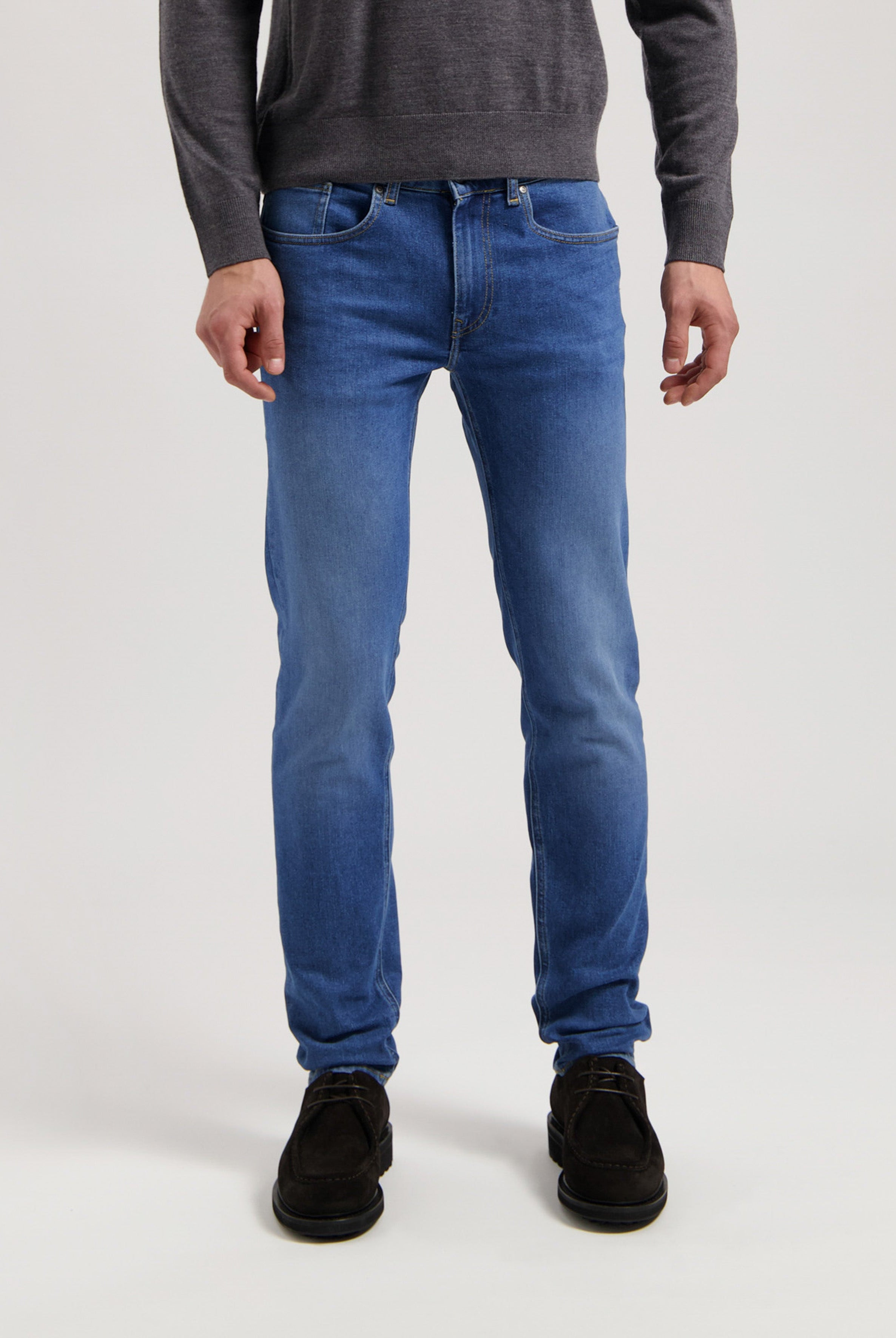 Sustainable MUD Jeans in dark blue denim, crafted ethically from organic cotton, paired with a casual gray t-shirt.
