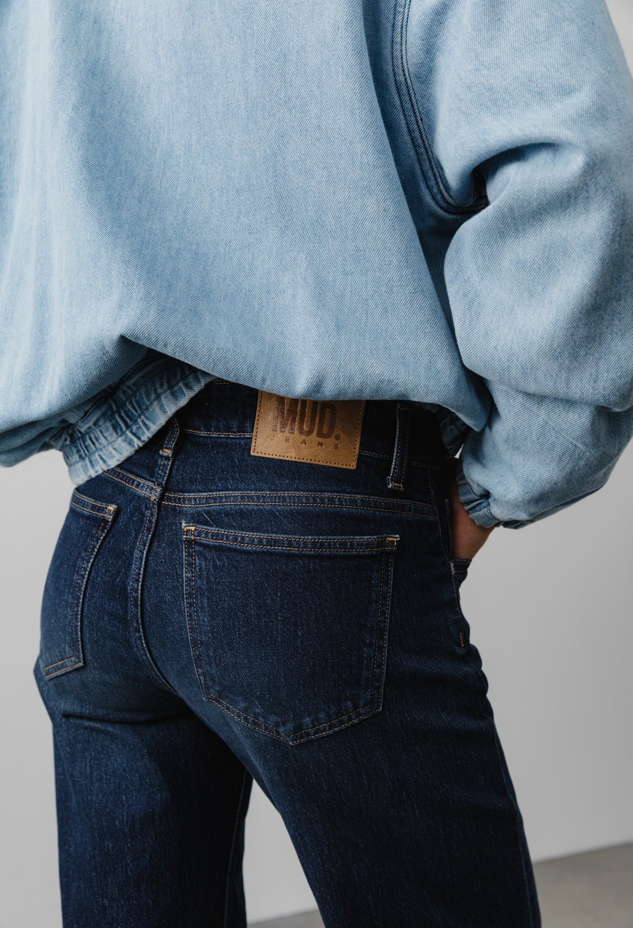 Person wearing dark blue MUD Jeans, featuring sustainable organic cotton denim, paired with a light blue denim jacket.