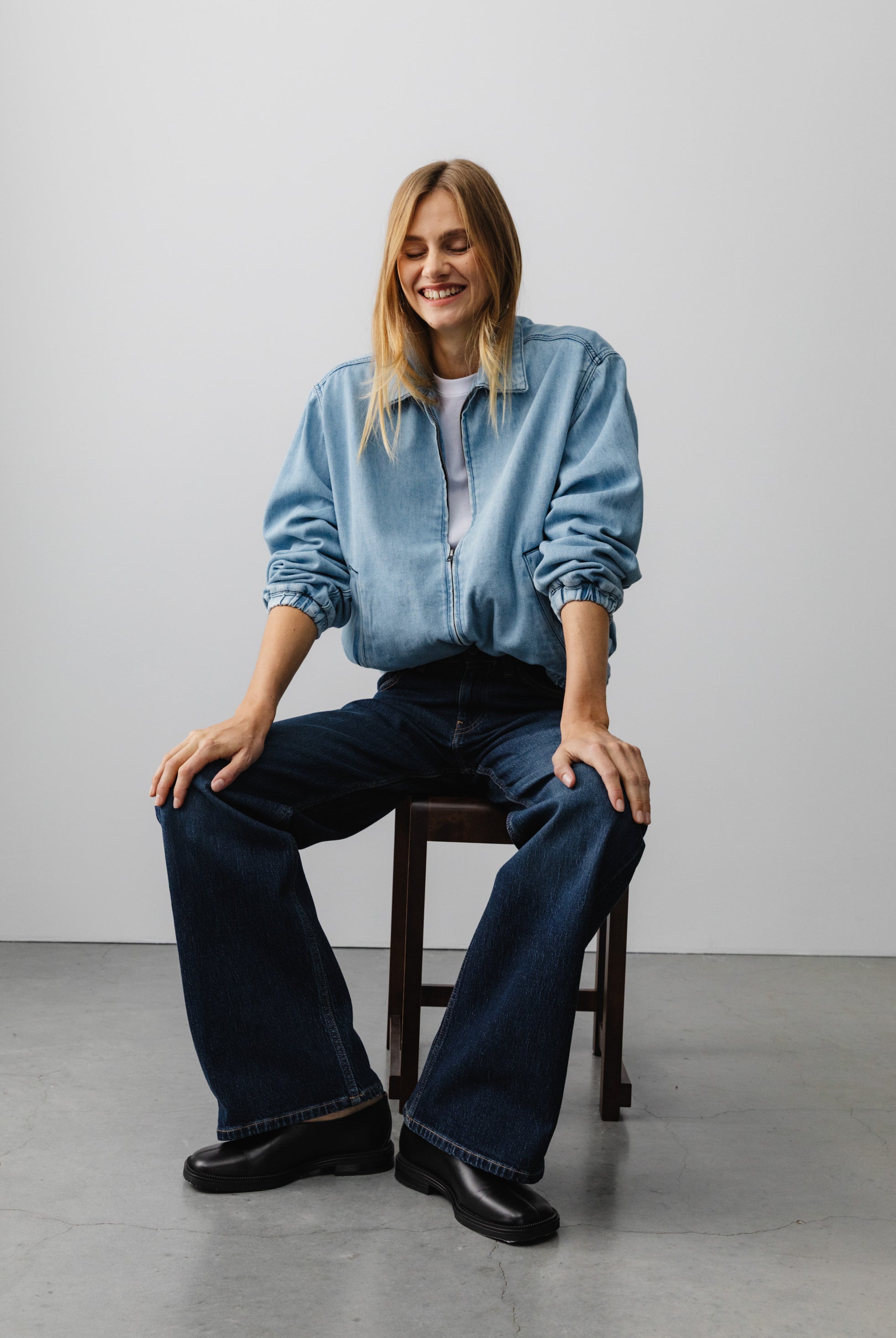 Casual outfit with light blue denim jacket and dark blue wide-leg jeans, worn with black shoes, sitting indoors.