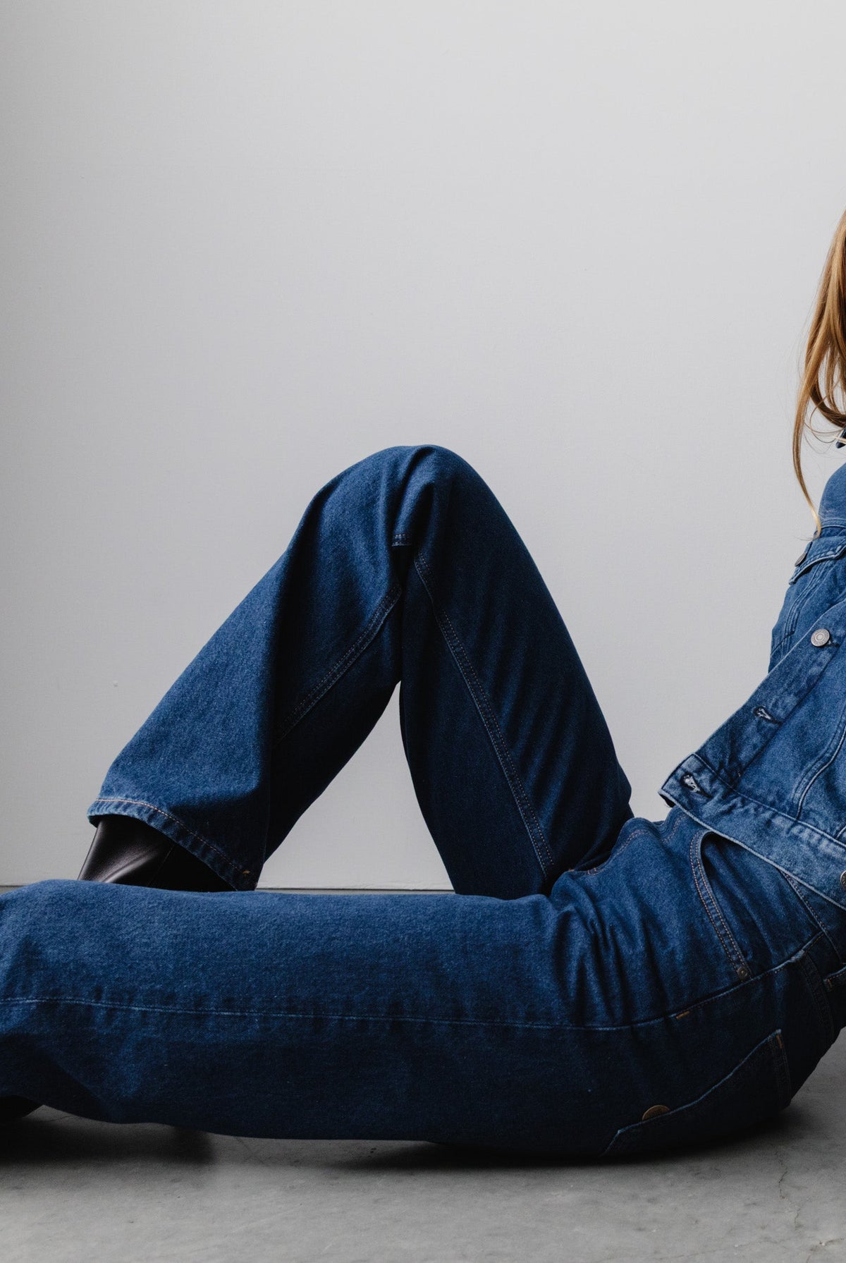 Casual blue denim ensemble featuring a relaxed-fit jacket and classic jeans, styled with a modern touch on a minimalist backdrop.