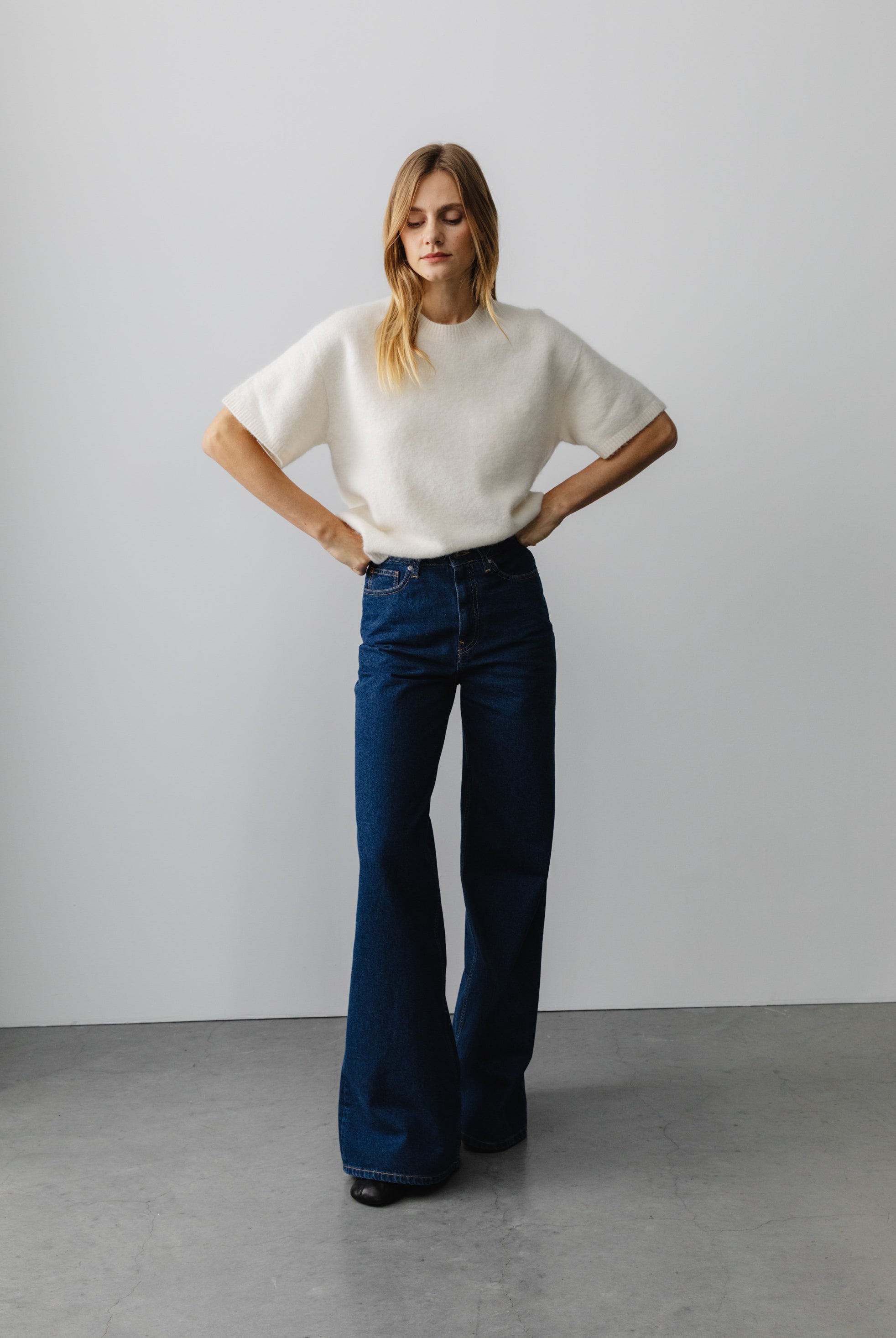 Wide-leg blue denim jeans paired with a soft white knit top, showcasing a casual fashion style.