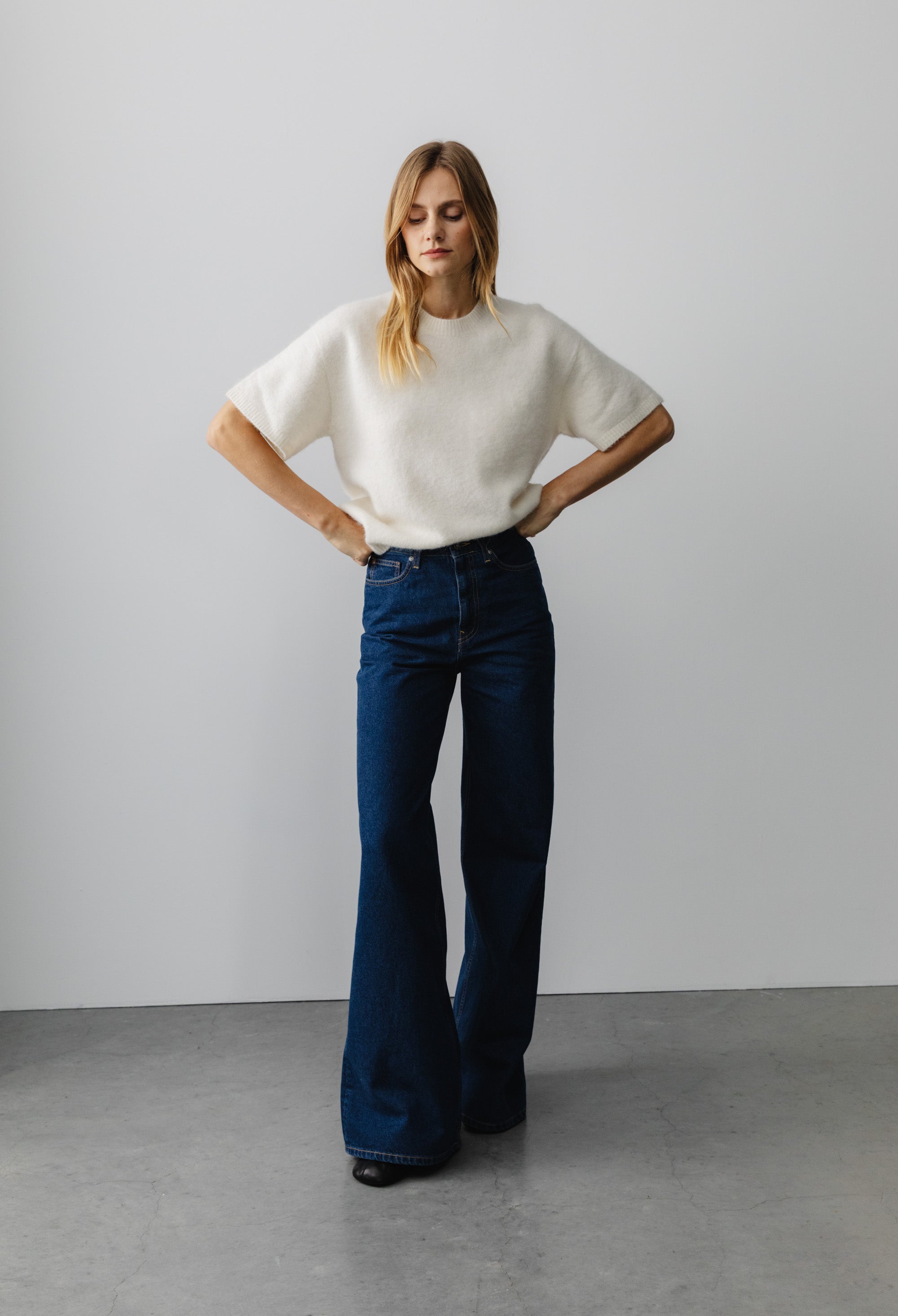 Wide-leg blue denim jeans paired with a soft white knit top, showcasing a casual fashion style.