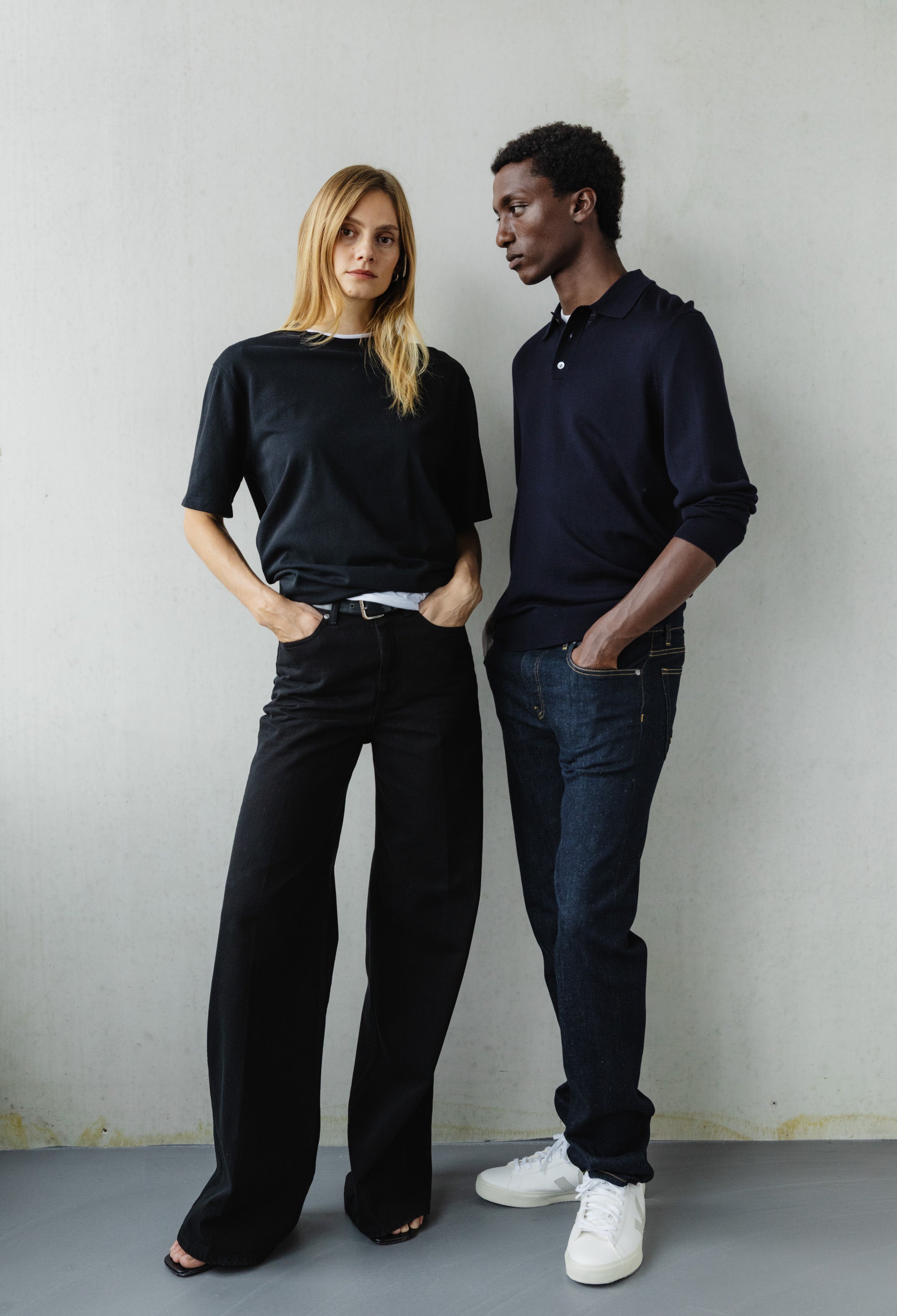 Fashion-forward duo in chic black and navy outfits, showcasing modern casual style in a minimalist setting.