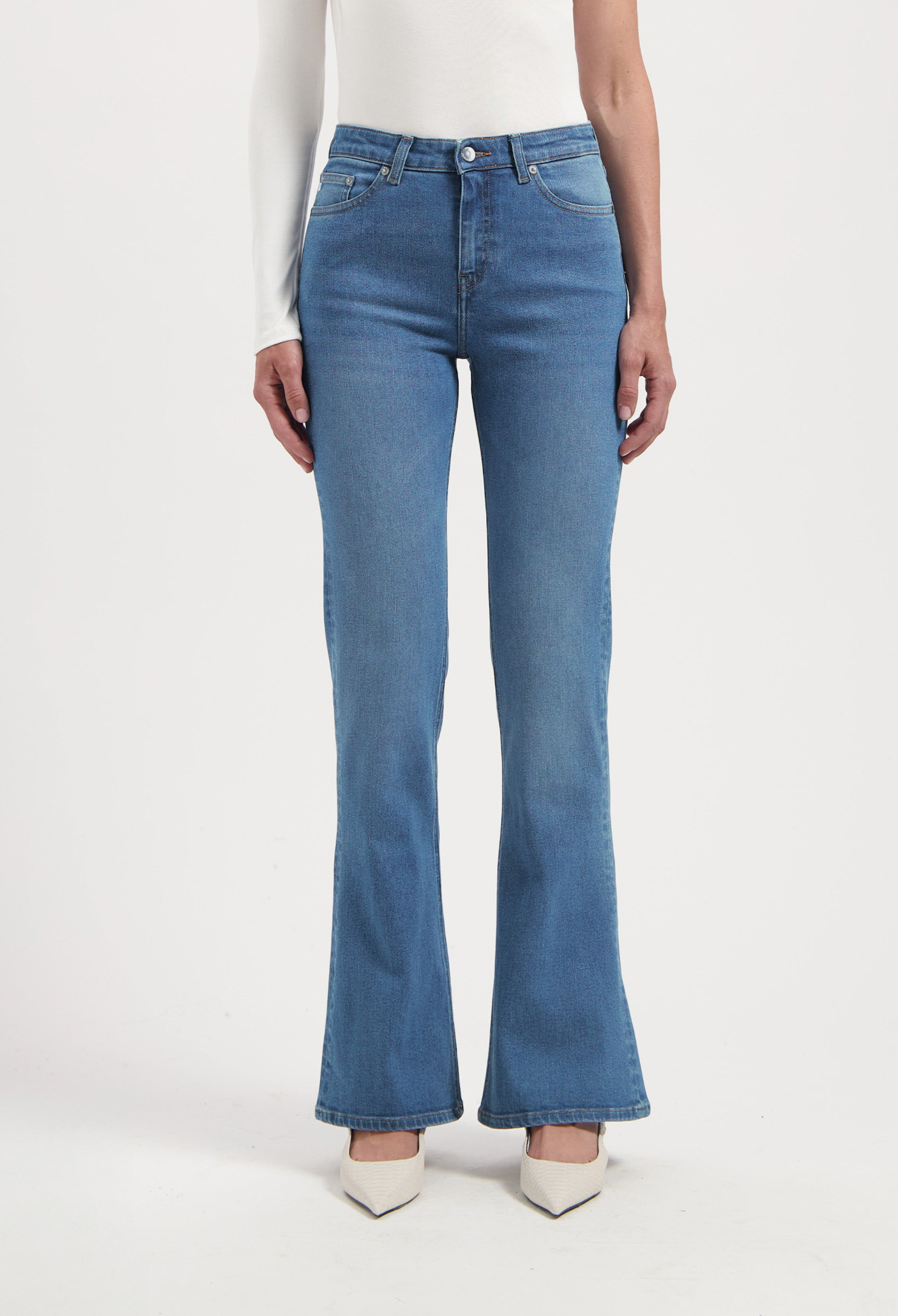 High-waisted, light blue flared jeans paired with a long-sleeve white top, showcasing a stylish casual outfit.