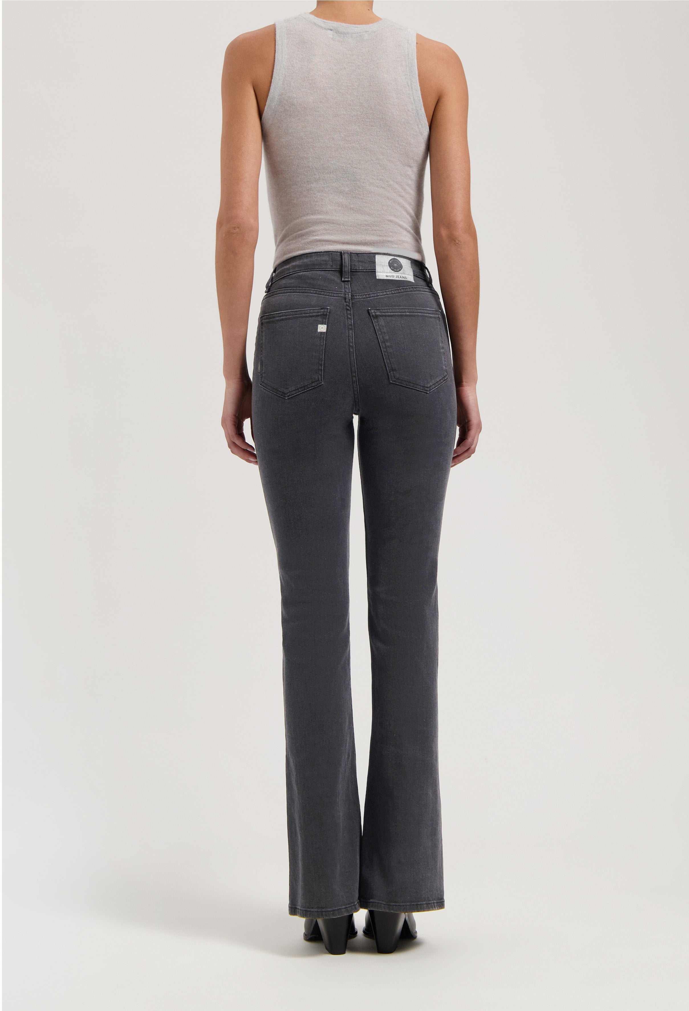 Back view of gray, high-waisted flare jeans from MUD Jeans, paired with a fitted sleeveless light gray top.