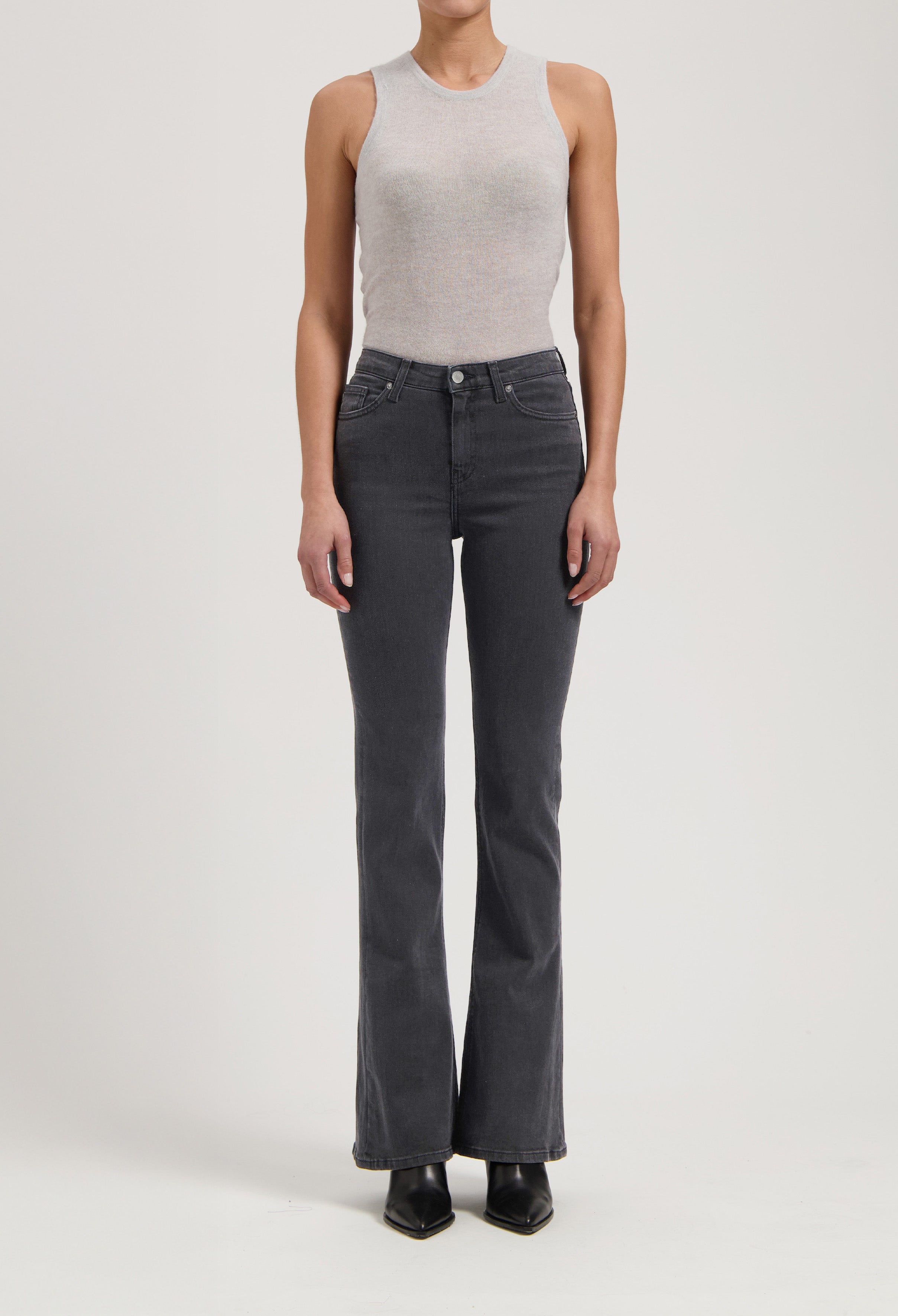 Gray sleeveless top paired with high-waisted black denim jeans, showcasing a minimalist and modern fashion style.