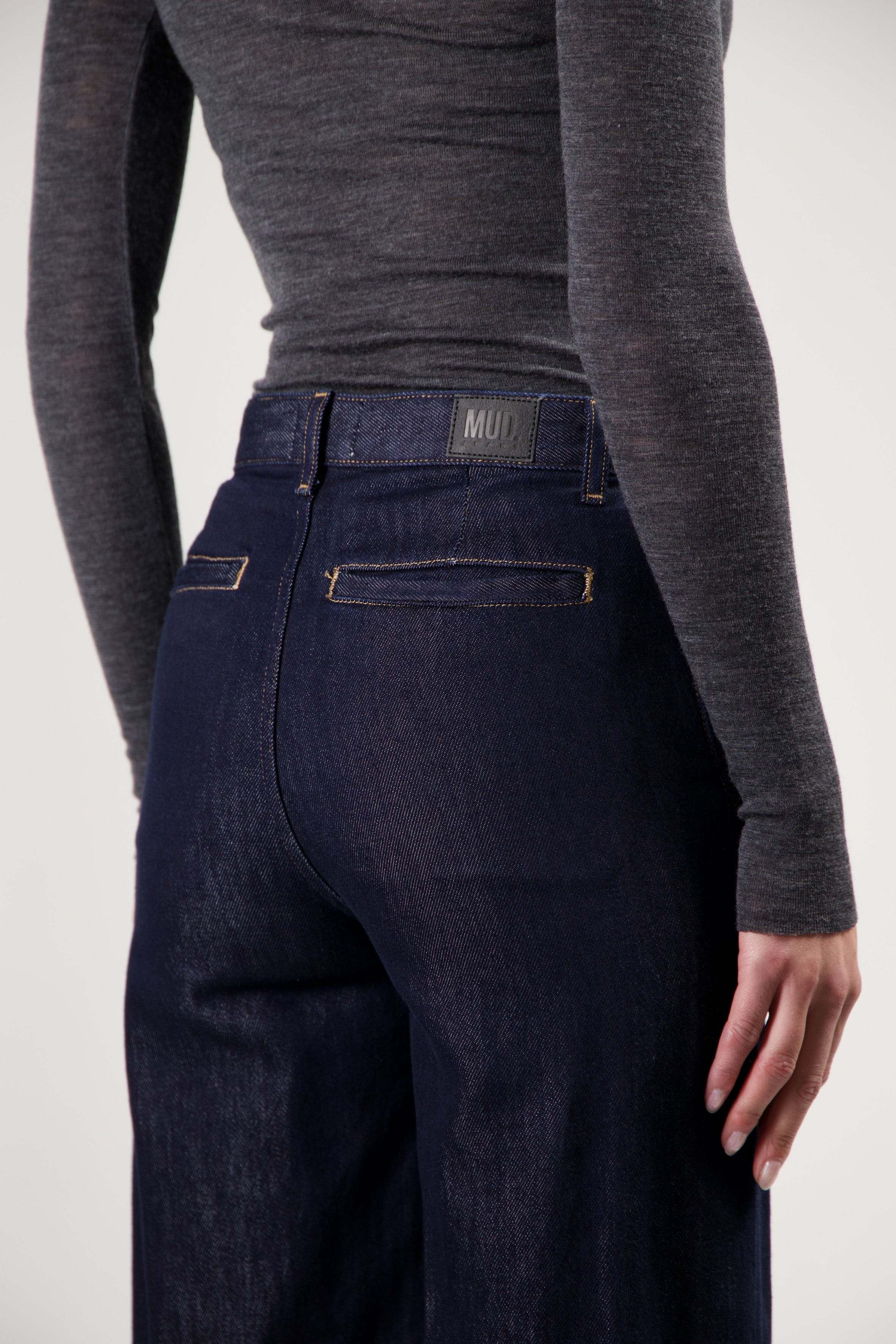 Dark blue MUD Jeans crafted from organic cotton, featuring wide-leg fit, paired with a charcoal gray long-sleeve top.