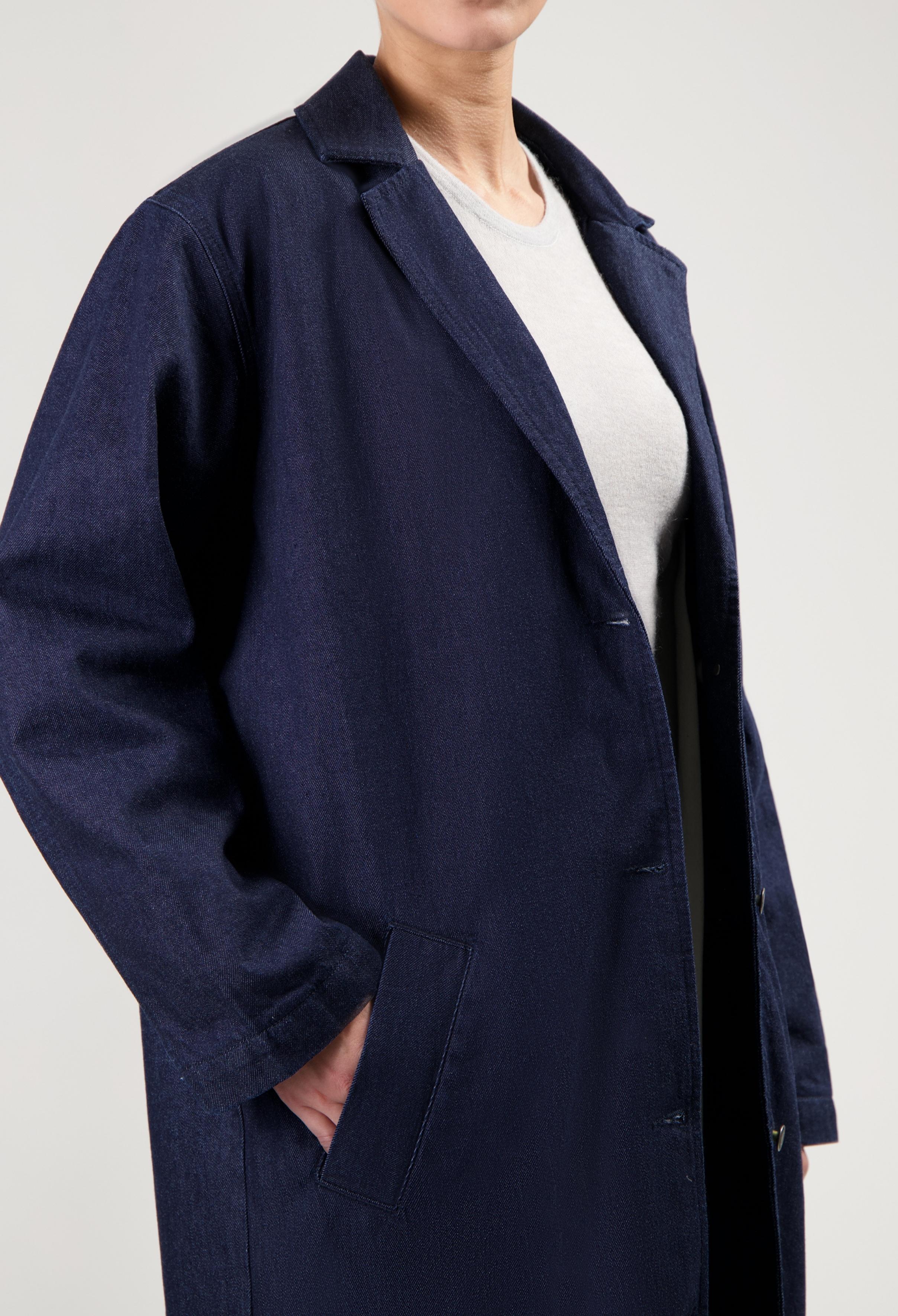 Navy blue denim coat worn over a light gray shirt, showcasing classic style with side pocket and button details.