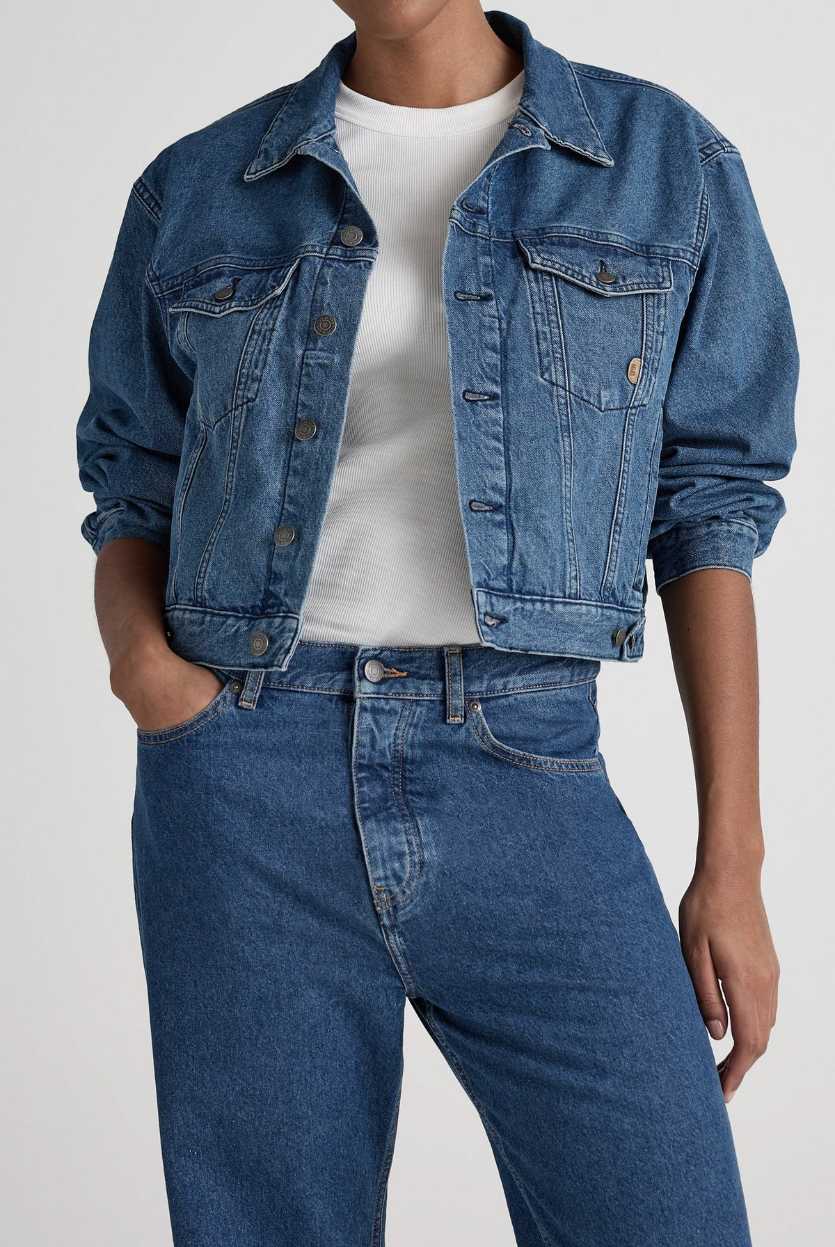Classic denim jacket and jeans set in medium blue, paired with a white ribbed t-shirt, showcasing casual chic style.