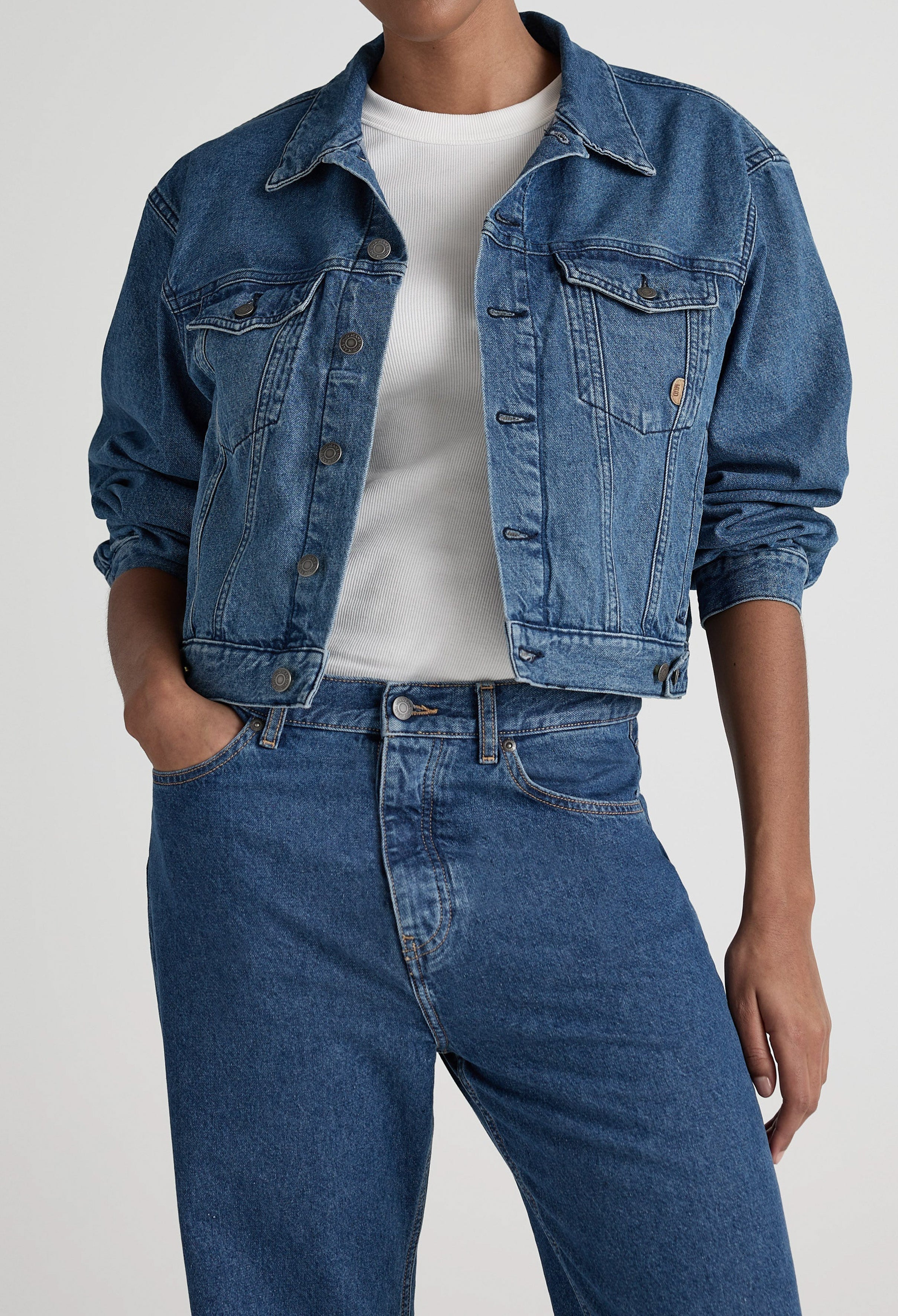 Classic denim jacket and jeans set in medium blue, paired with a white ribbed t-shirt, showcasing casual chic style.