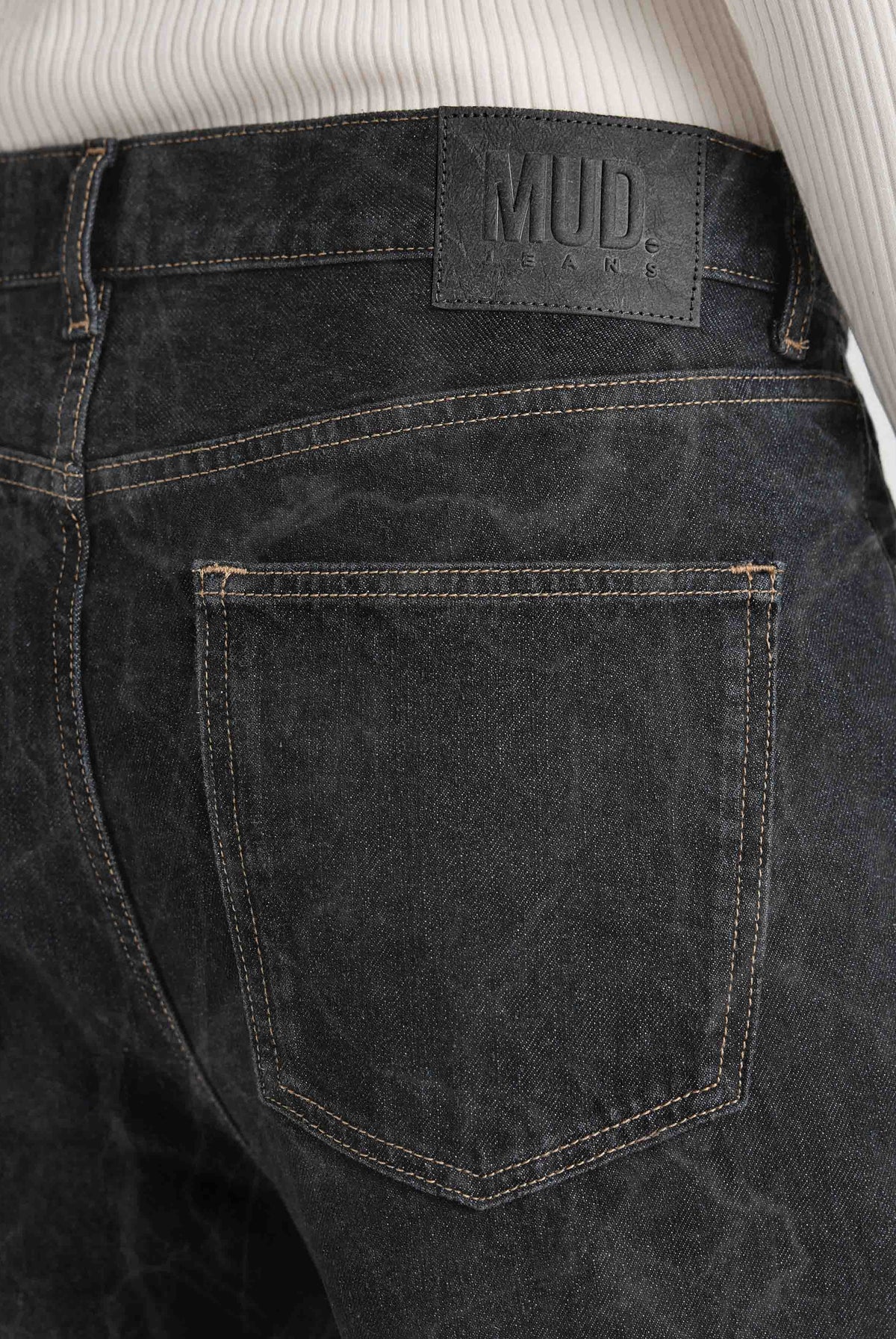 Back view of dark gray MUD Jeans made from organic cotton, highlighting sustainable material and leather logo patch.