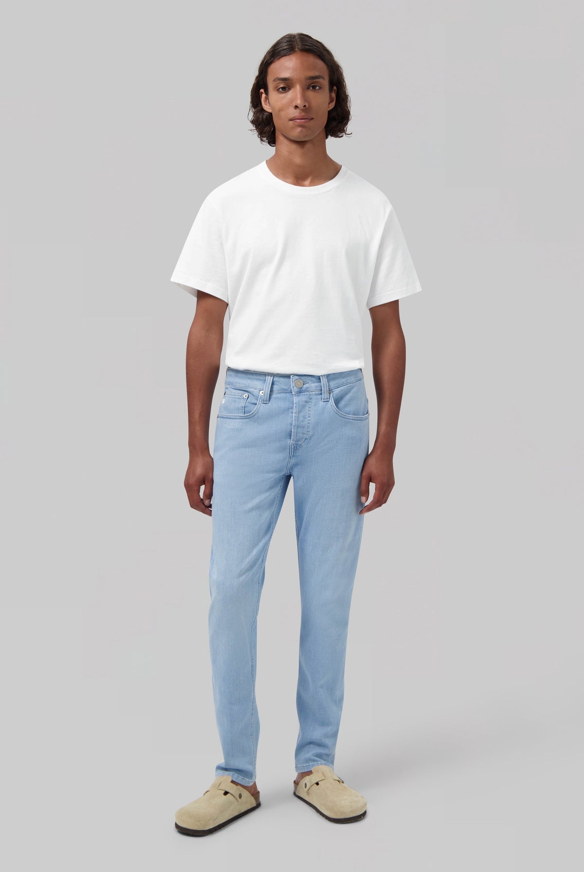 Sustainable MUD Jeans in classic blue denim, worn with a white shirt and navy sweater, showcasing ethical fashion.