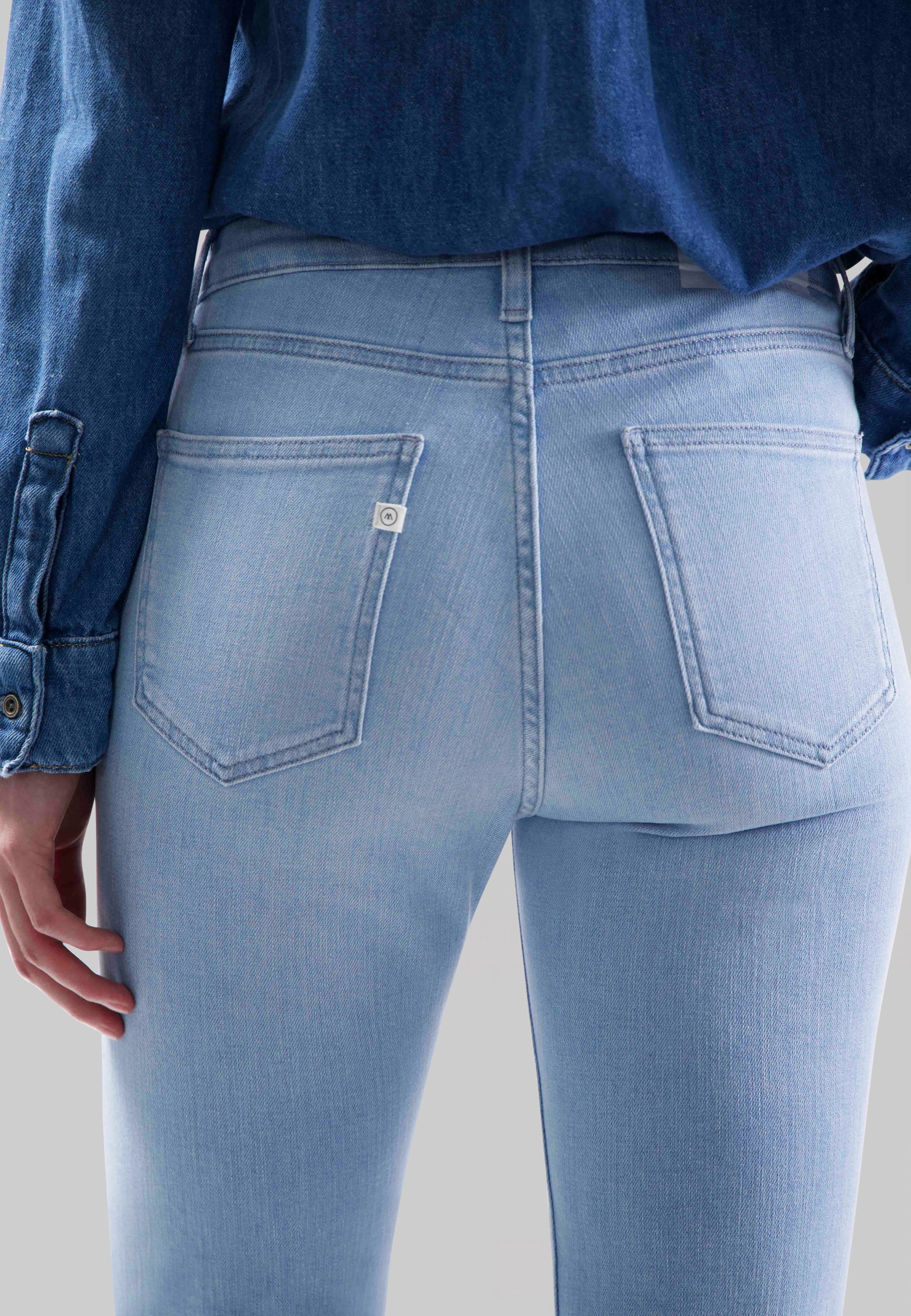 Light blue, high-waisted denim jeans with back pockets, paired with a dark blue denim shirt, showcasing a casual style.
