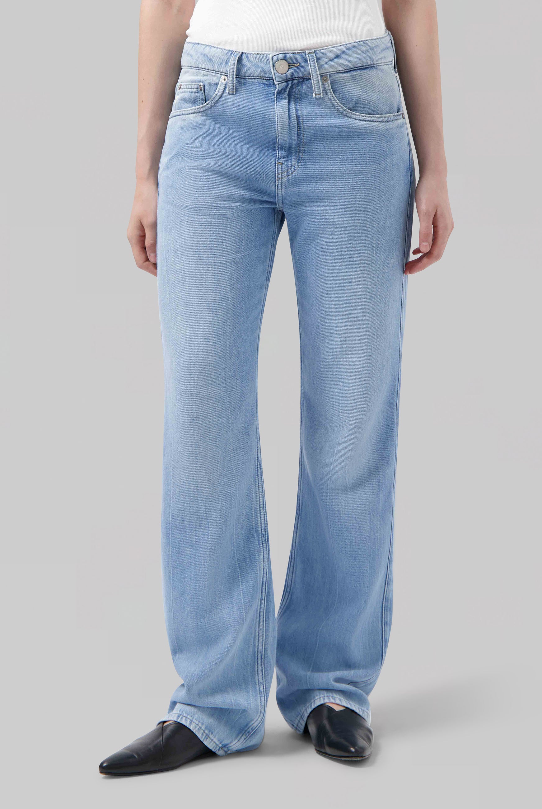 Light blue, high-waisted jeans made from denim, featuring a straight-leg silhouette, styled with a white top and black shoes.