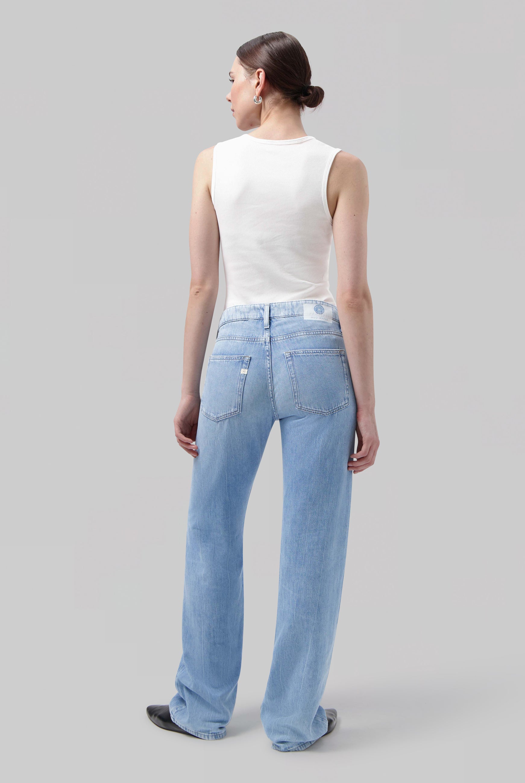 Wide-leg light blue jeans in soft denim, paired with a white sleeveless top, creating a casual chic look.