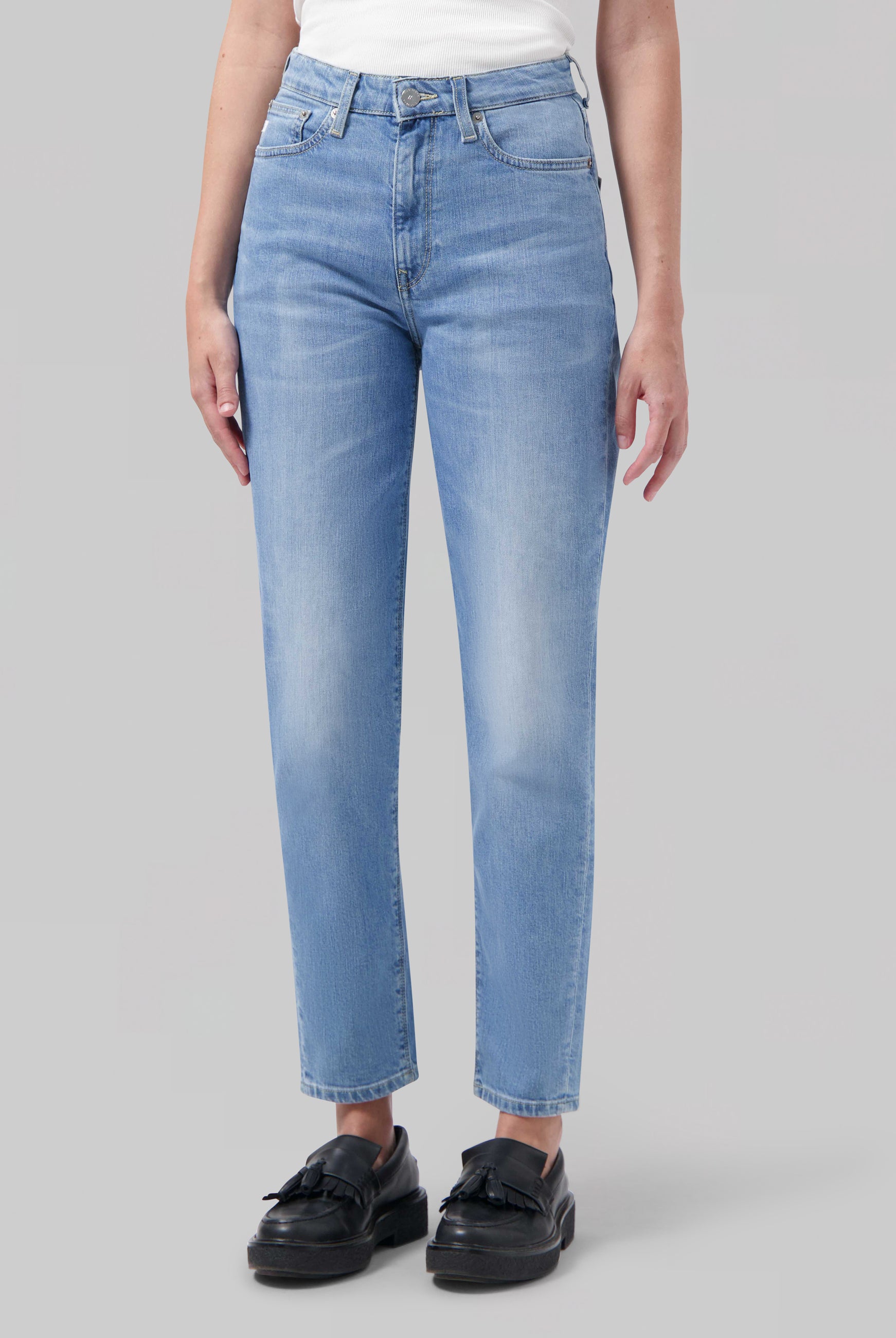 Light blue, straight-leg jeans in faded denim, worn with a white top and black shoes, showcasing casual style clothing.