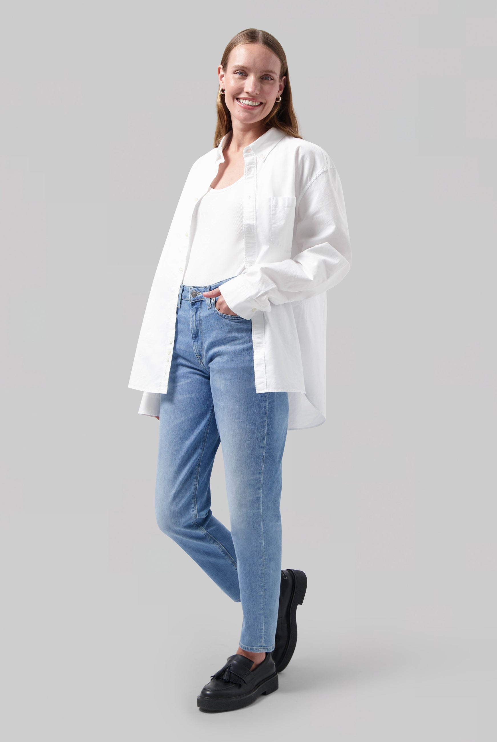 Casual outfit featuring light blue jeans and a white shirt, paired with black loafers, highlighting relaxed fashion style.