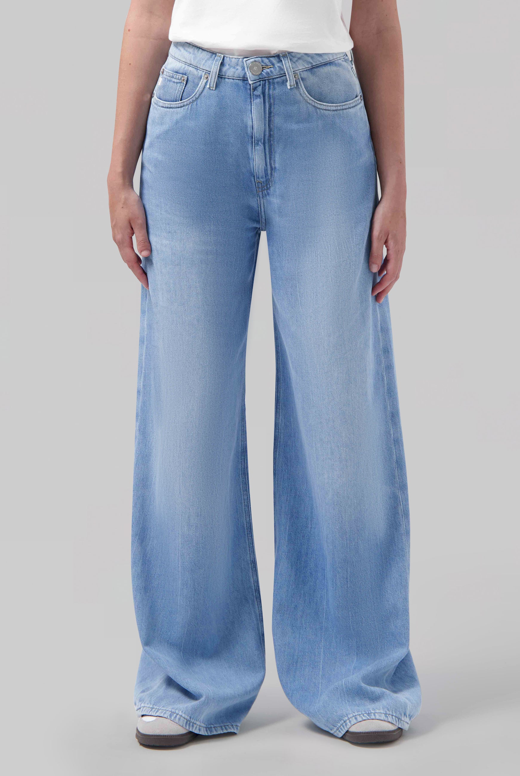 High-waisted wide-leg light blue jeans displayed on model, paired with a plain white top, showcasing casual style fashion.