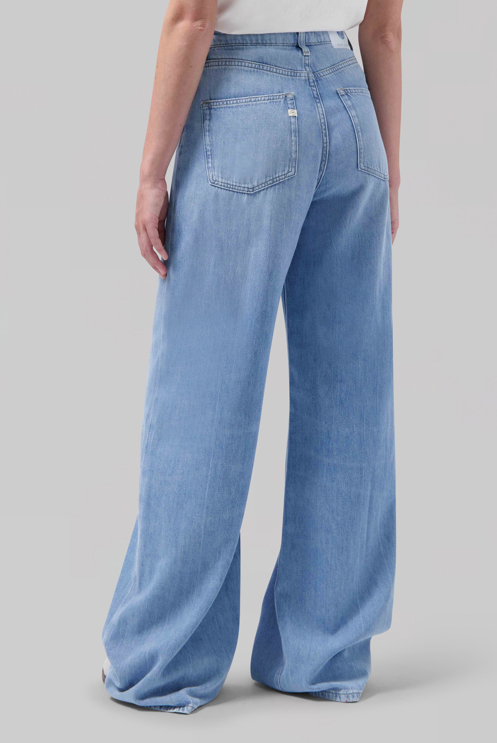 Wide-leg light blue jeans made from denim, showing a rear view with a high waist and two back pockets, paired with a white top.