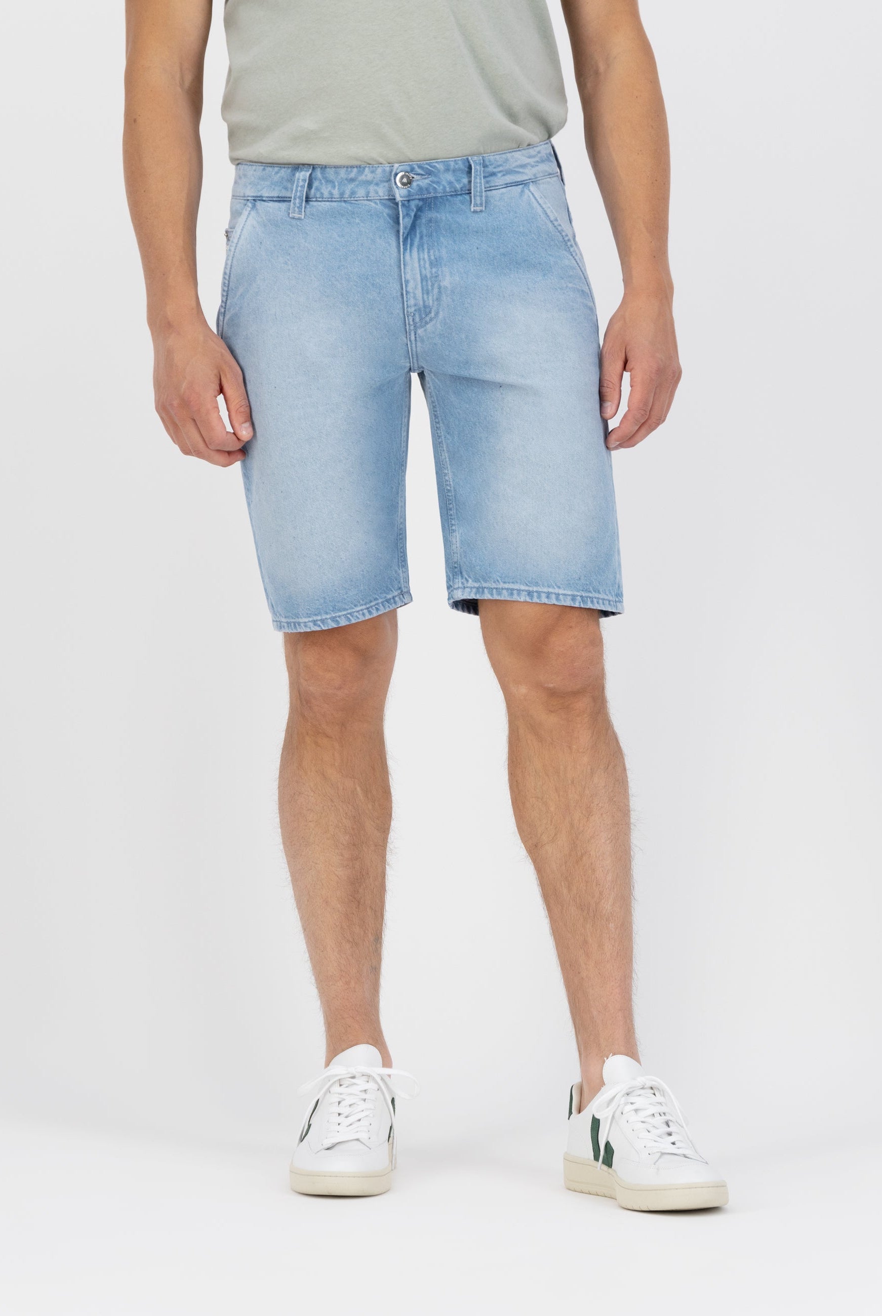 Sustainable MUD Jeans in light blue denim, featuring a classic straight fit, paired with a black sweater for an ethical look.