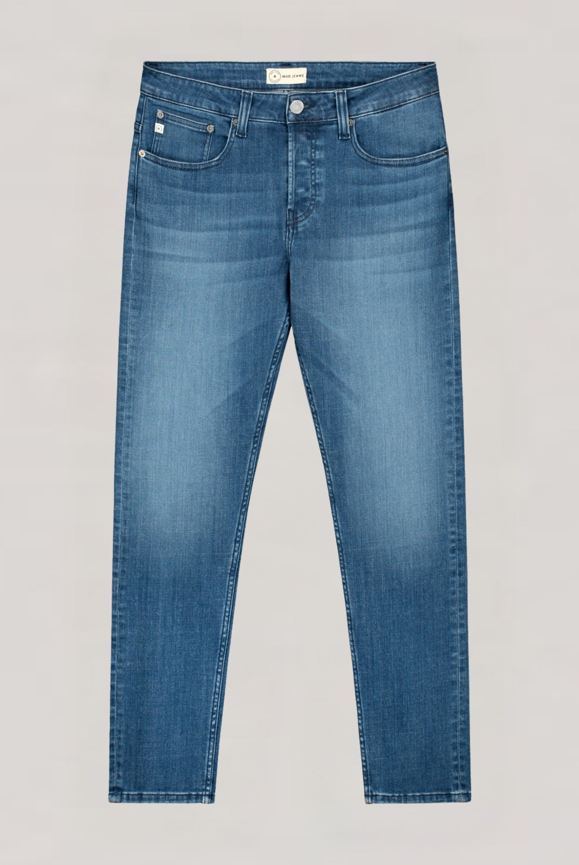 Sustainable MUD Jeans in classic blue denim, styled with a dark blue jacket, highlighting ethical fashion in a street scene.