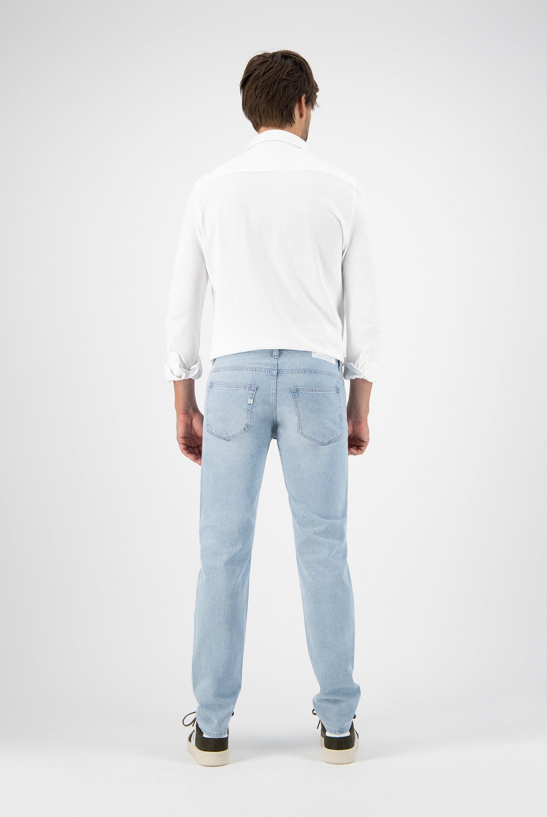 Sustainable MUD Jeans in light blue denim, crafted ethically, paired with a plain white tee, highlighting eco-friendly fashion.