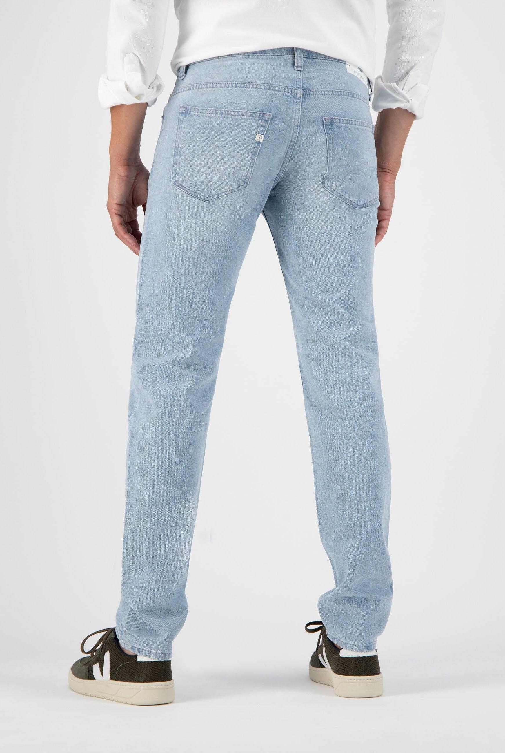 Sustainable MUD Jeans crafted from light blue denim, featuring a classic fit, paired with casual beige shoes.