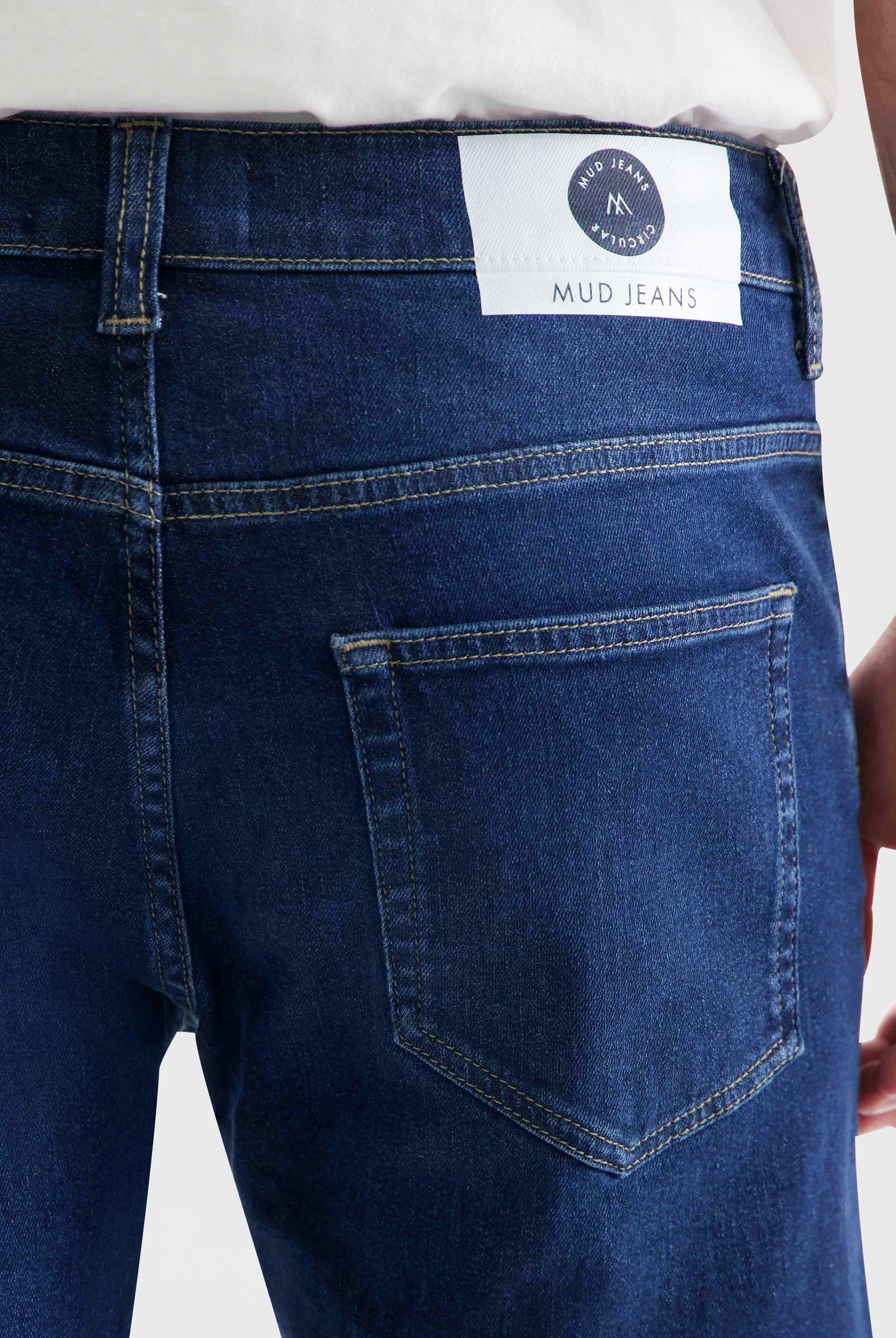 Sustainable MUD Jeans sleeveless jacket in dark blue denim, paired with a matching blue cap, showcasing eco-friendly fashion.