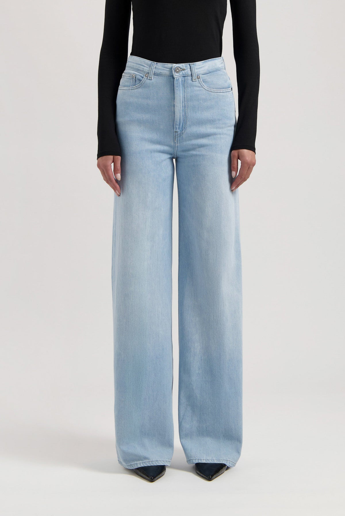 Light blue, high-waisted wide-leg jeans paired with a long-sleeve black top, showcasing a modern casual style.