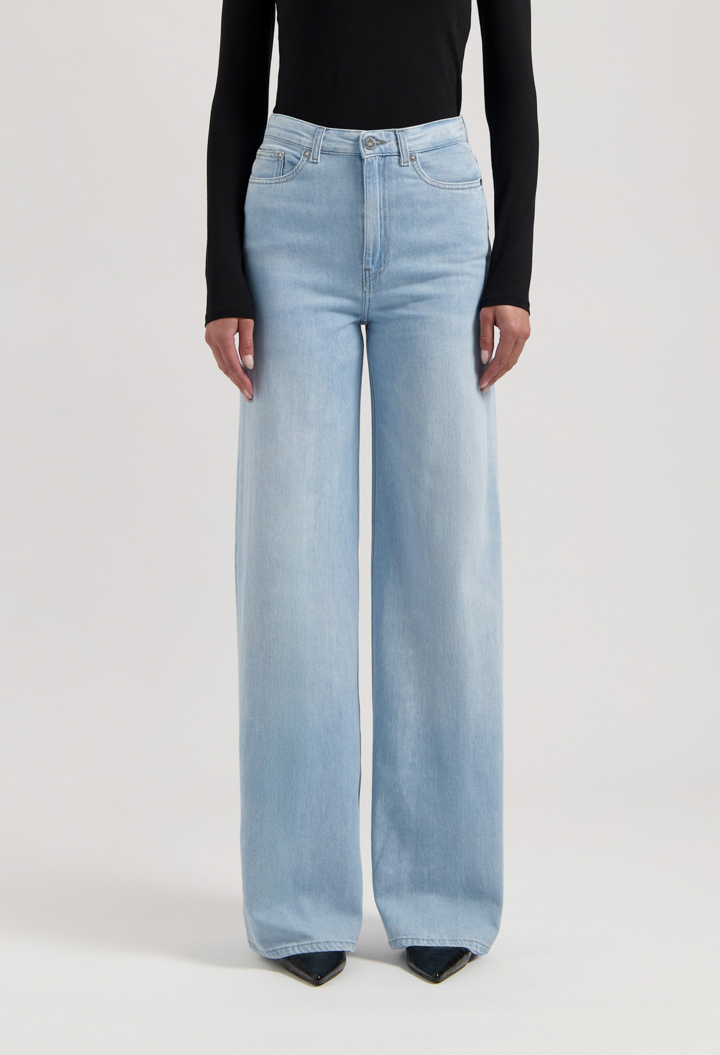 Light blue, high-waisted wide-leg jeans paired with a long-sleeve black top, showcasing a modern casual style.