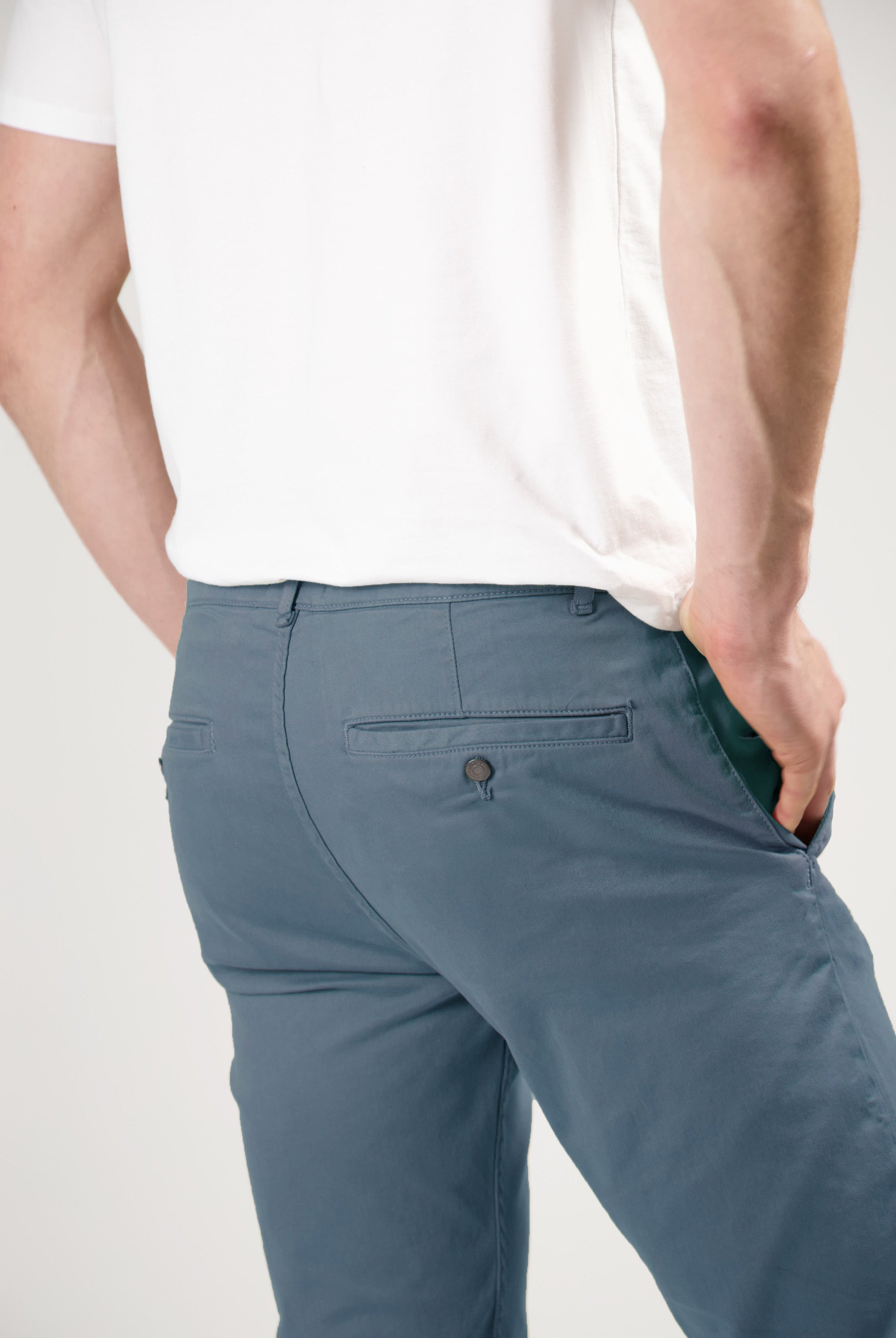 Sustainable MUD Jeans in light blue organic cotton, slim fit, paired with a gray T-shirt and white sneakers, side view.