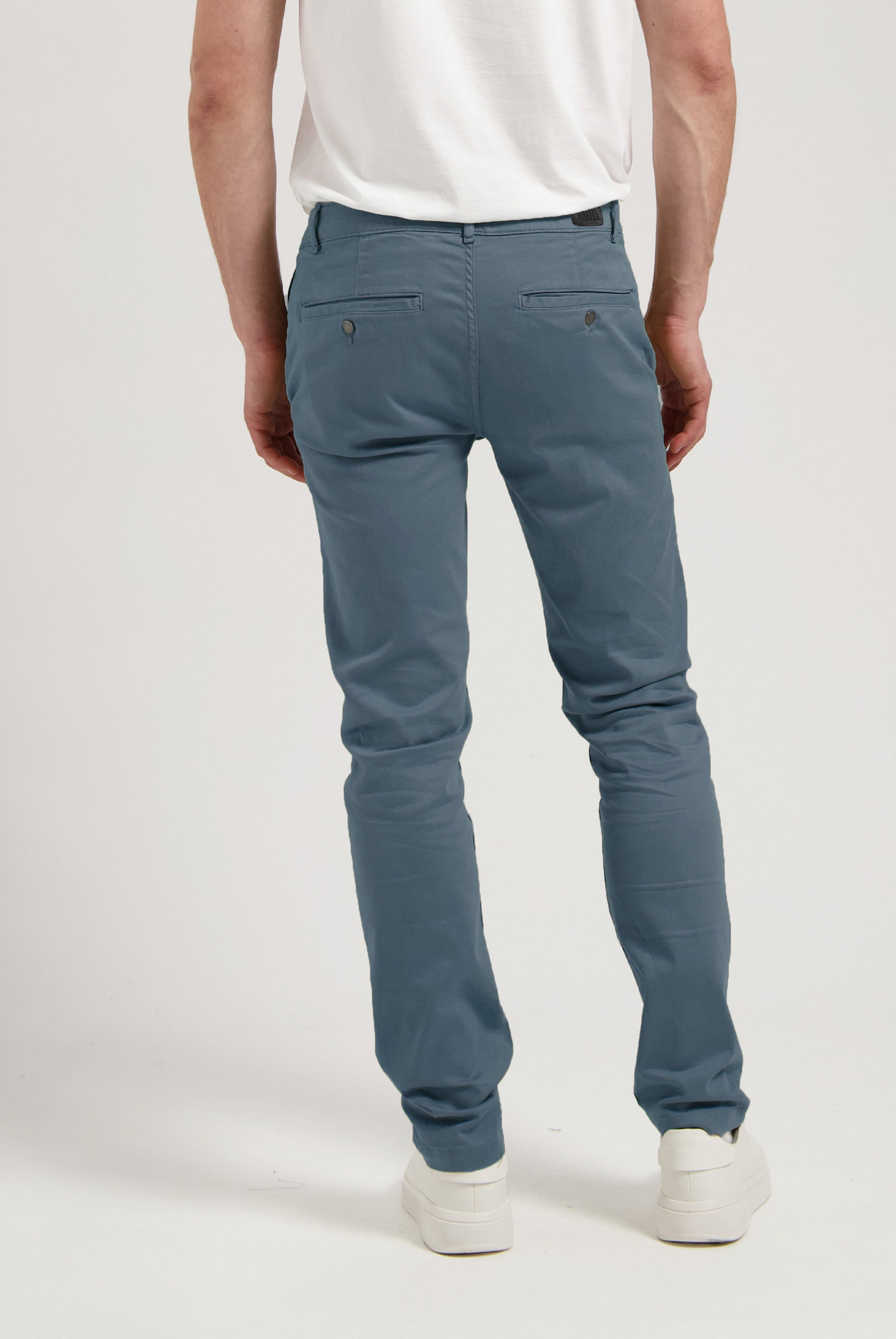 Sustainable MUD Jeans in light blue denim, ethically made, paired with a gray shirt and white sneakers for a casual look.