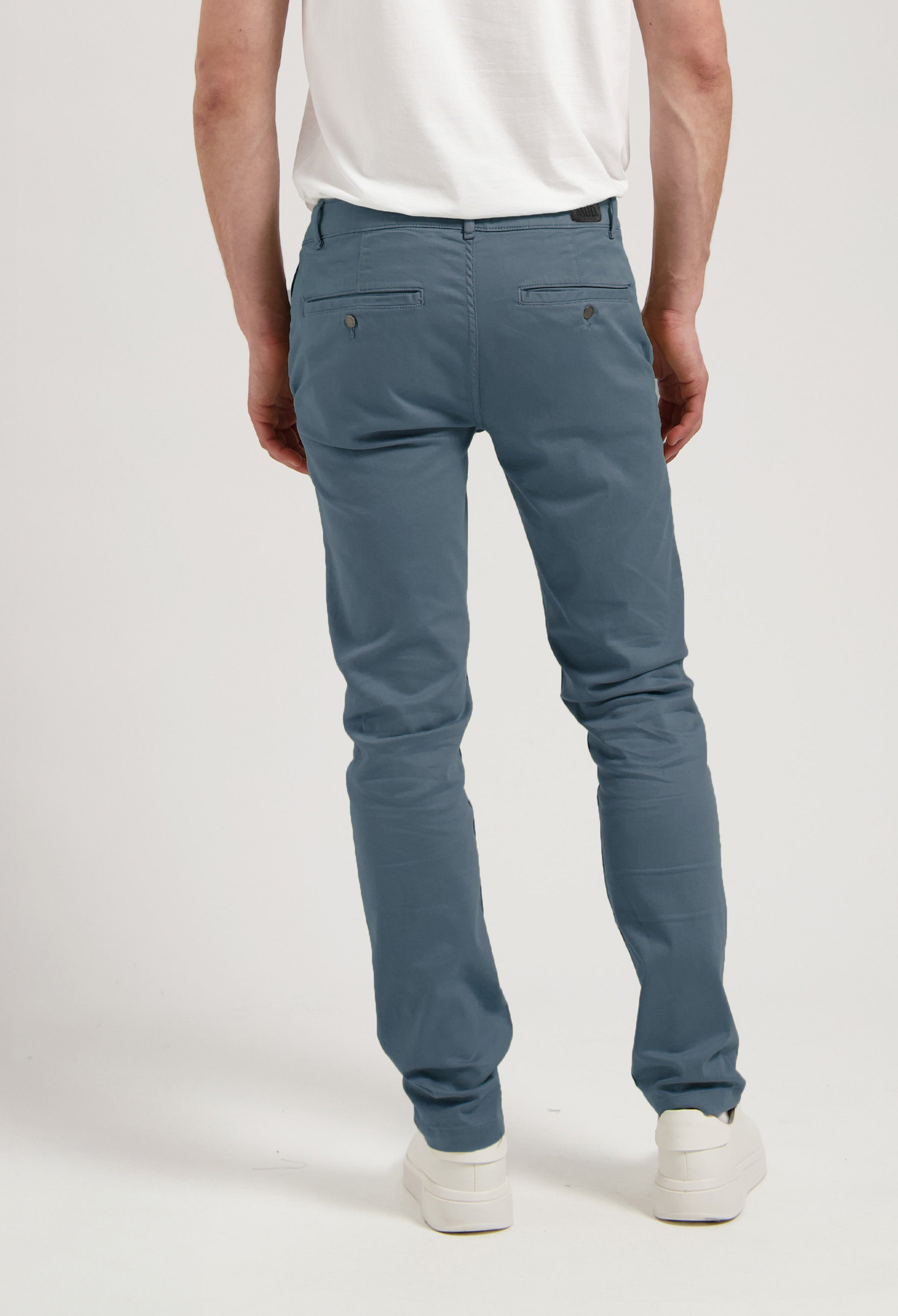 Sustainable MUD Jeans in light blue denim, ethically made, paired with a gray shirt and white sneakers for a casual look.