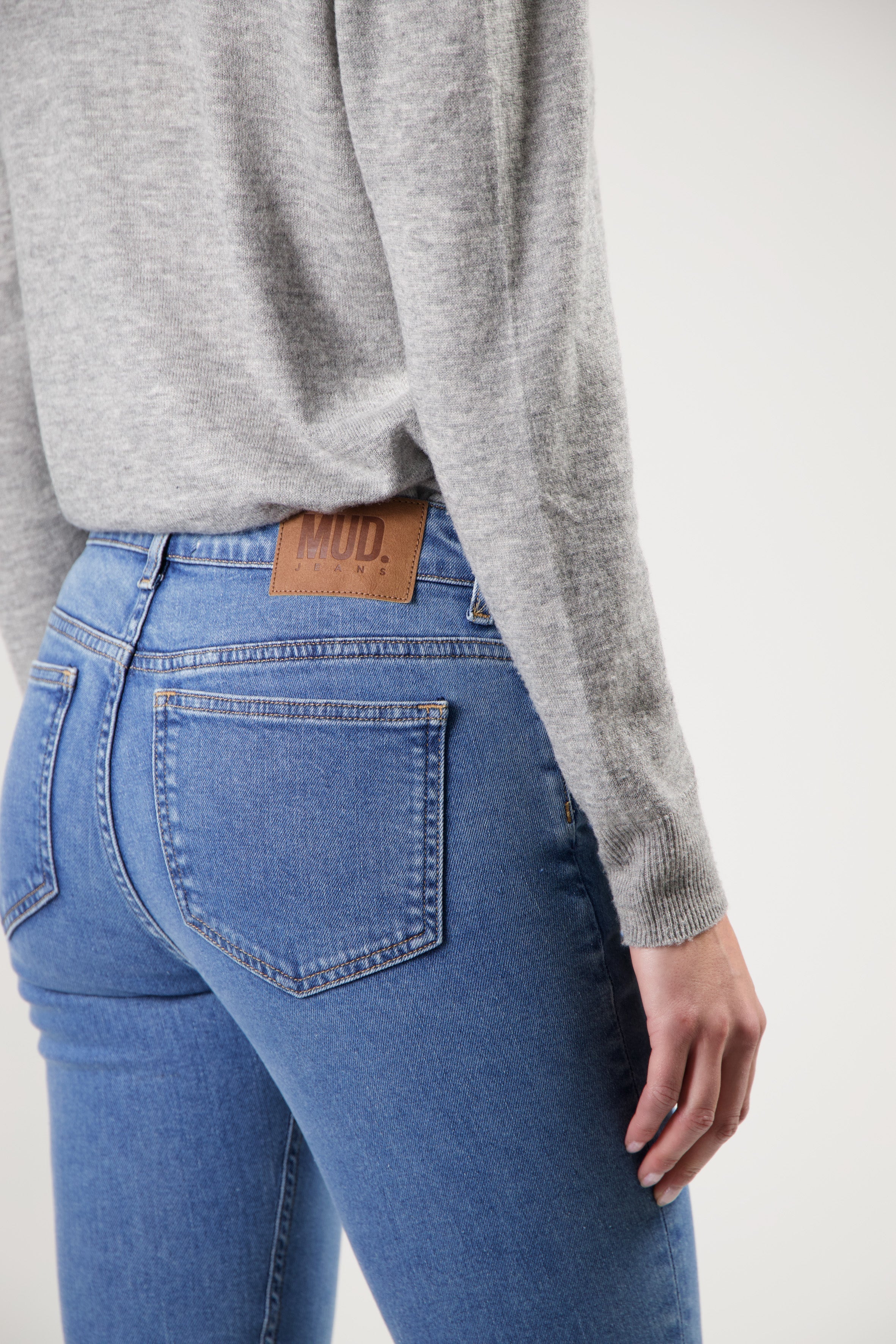 Light blue MUD Jeans in organic cotton, featuring slim-fit design, paired with a soft gray knit top.