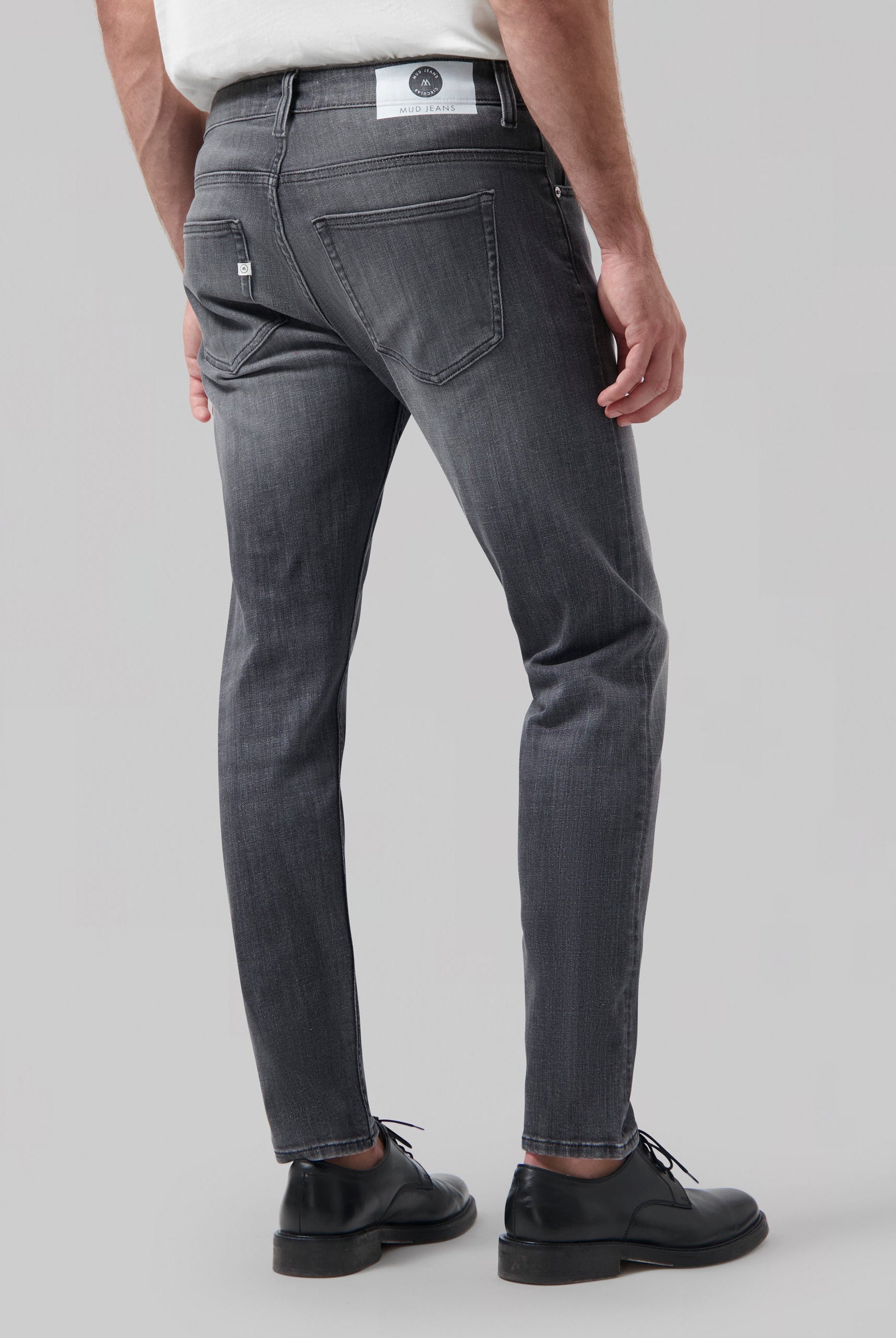 Sustainable light blue denim jeans by MUD Jeans, crafted from organic cotton, paired with a simple white T-shirt.