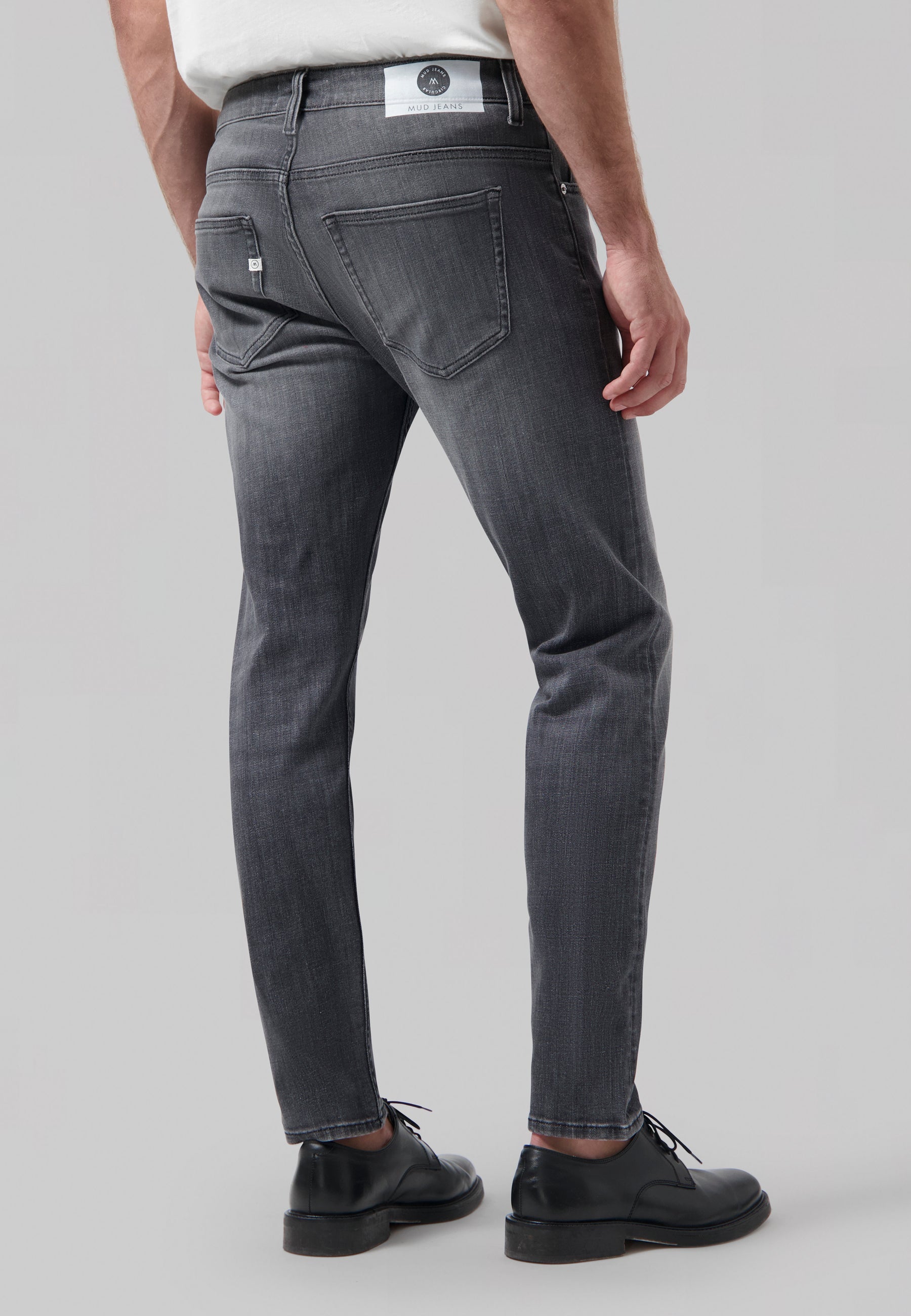 Sustainable light blue denim jeans by MUD Jeans, crafted from organic cotton, paired with a simple white T-shirt.