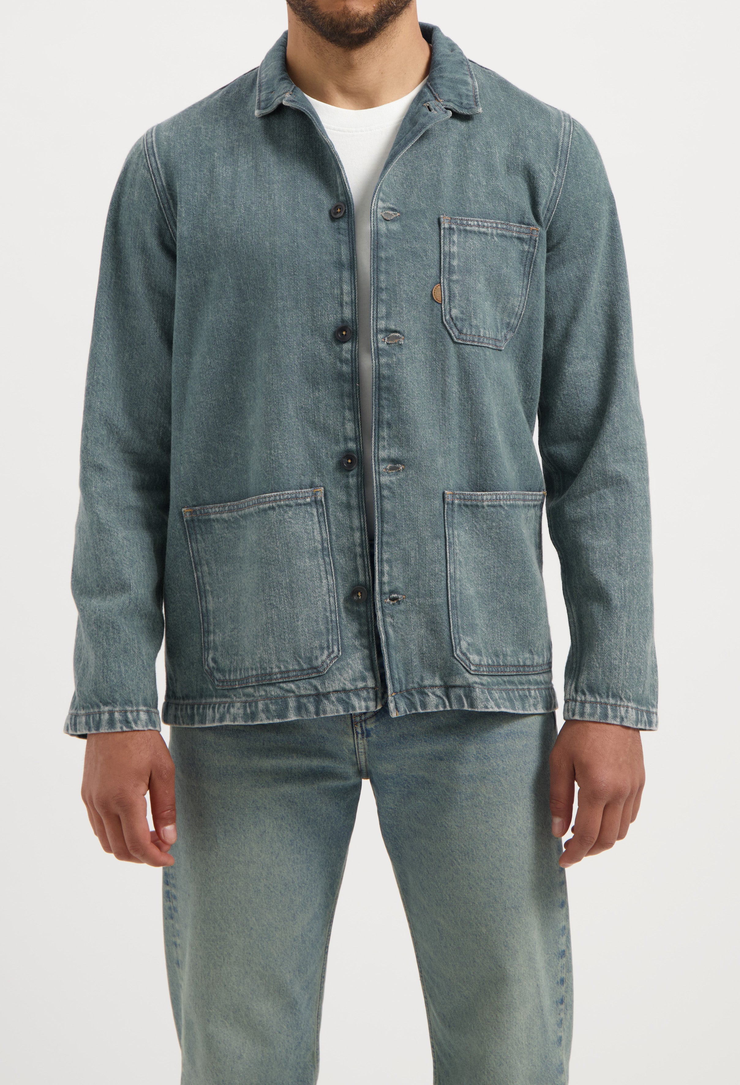 Sustainable MUD Jeans in light blue denim, crafted from ethical materials, paired with a casual gray T-shirt.