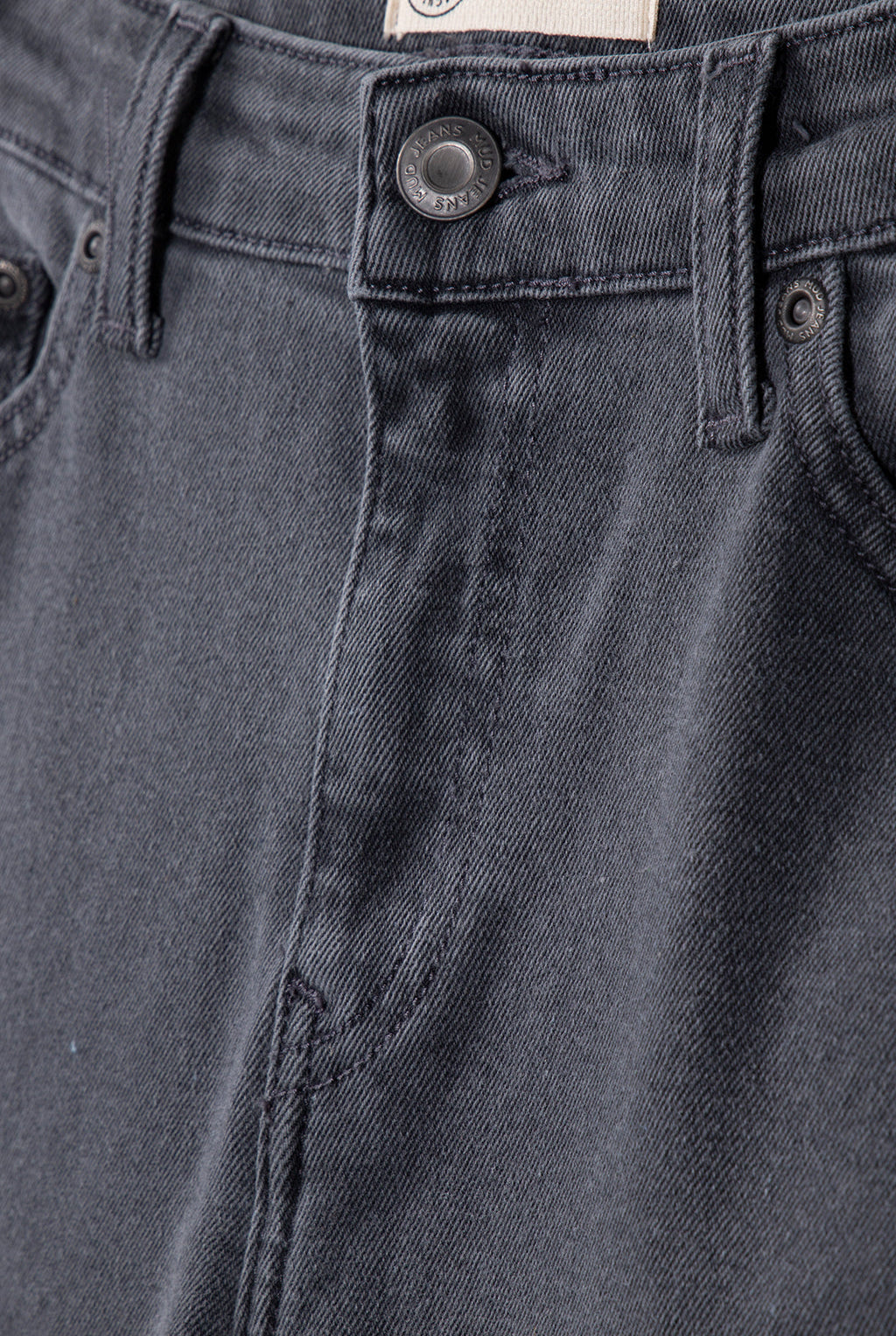 Close-up of sustainable dark gray denim jeans showcasing detailed stitching and a branded button on the waistband.