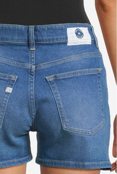Blue denim MUD Jeans shorts worn with a black top, showcasing sustainable fashion with classic pocket stitching.
