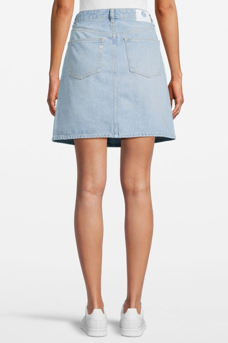 Light blue A-line denim skirt with back pockets and faded hem, worn by a person with white sneakers, showcasing casual style.