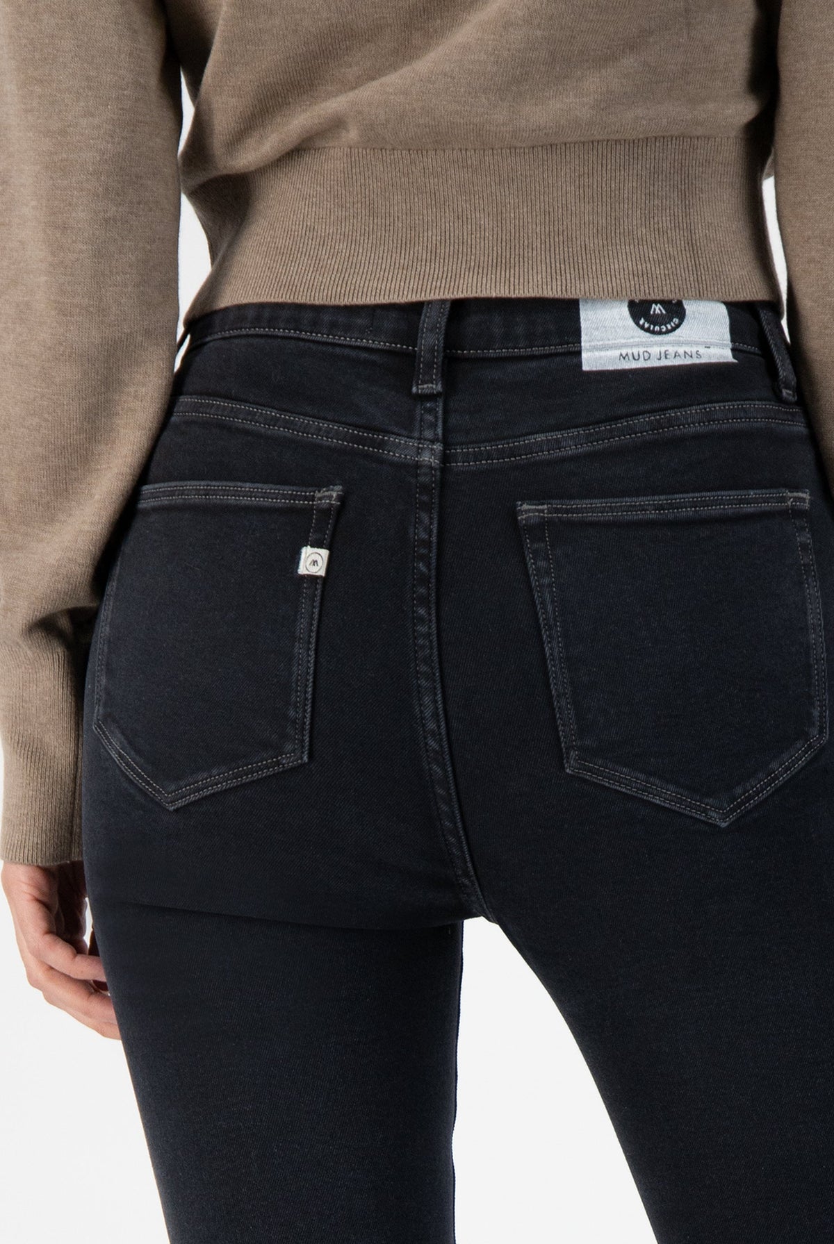 Stylish dark blue MUD Jeans crafted from organic cotton, featuring a slim-fit design worn with a cozy beige sweater.
