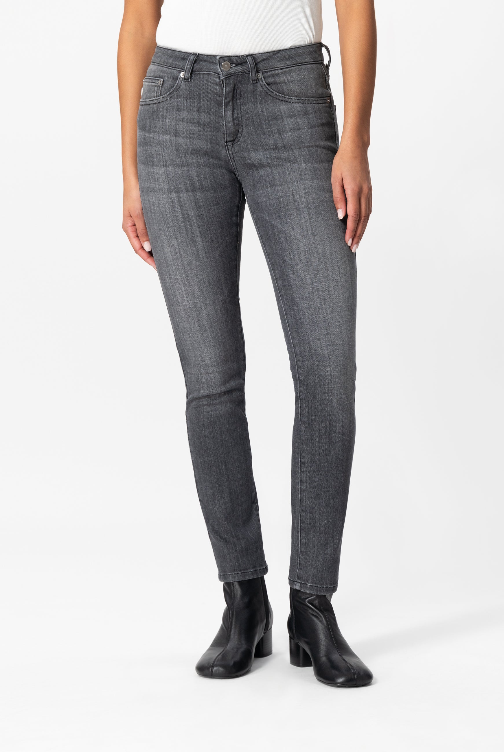 Slim-fit gray jeans made from sustainable fabric, paired with a white top and black ankle boots for a modern look.