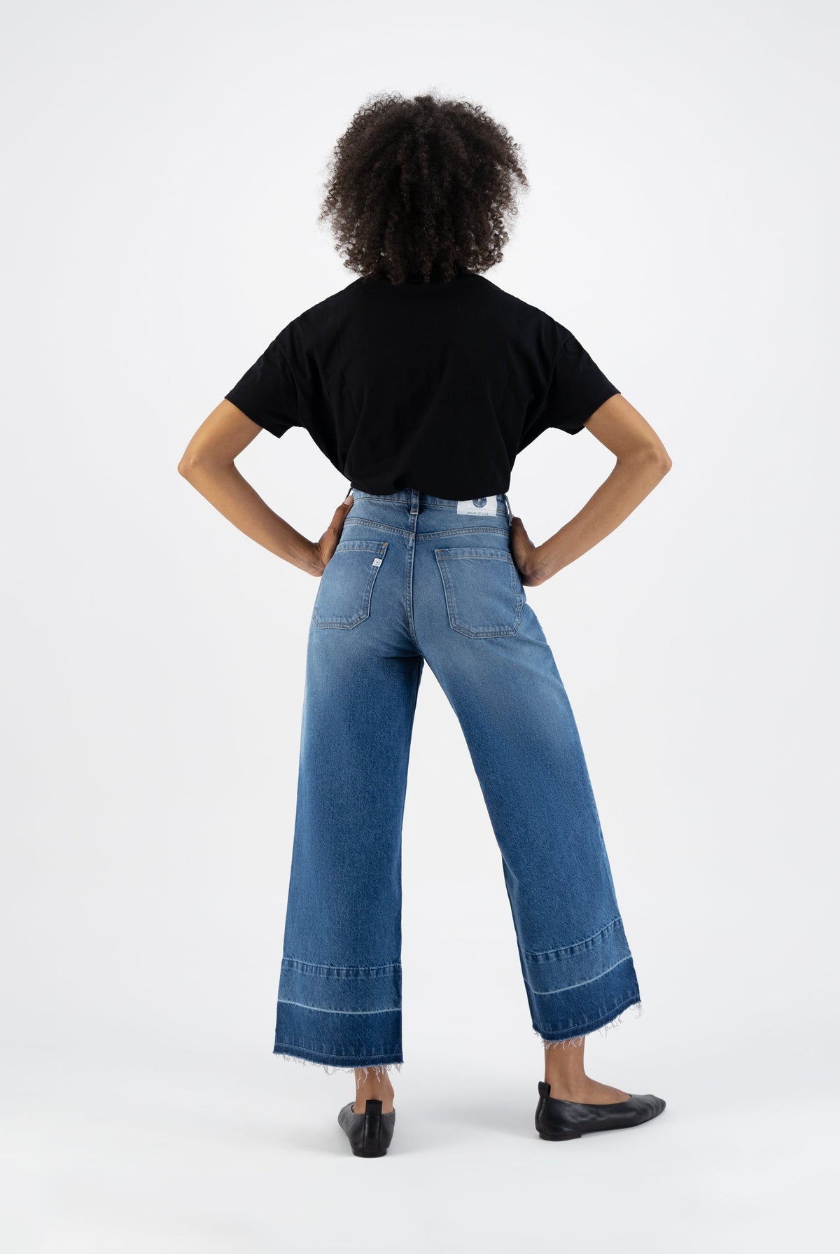 Wide-leg blue denim jeans paired with a black t-shirt, showcasing a casual and stylish back view of modern fashion.
