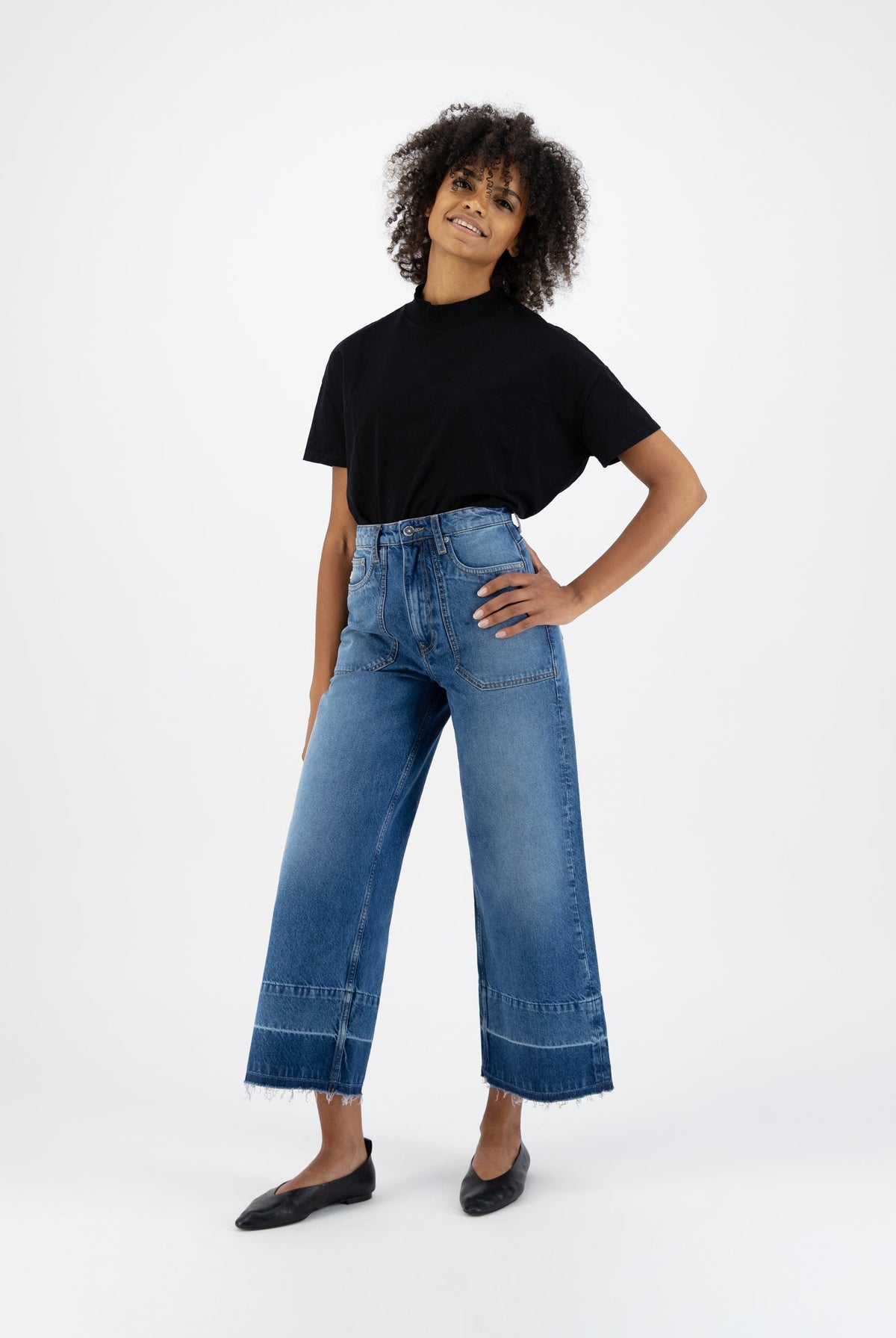 Casual fashion outfit featuring high-waisted, wide-leg blue denim jeans and a classic black t-shirt, perfect for everyday wear.