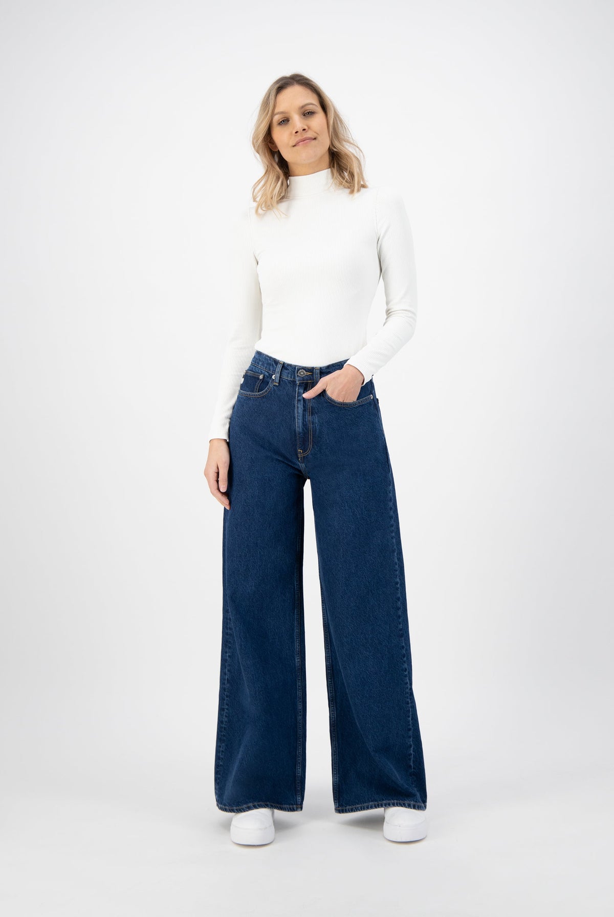 Wide-leg blue denim jeans paired with a white turtleneck sweater, showcasing a casual and chic fashion style.