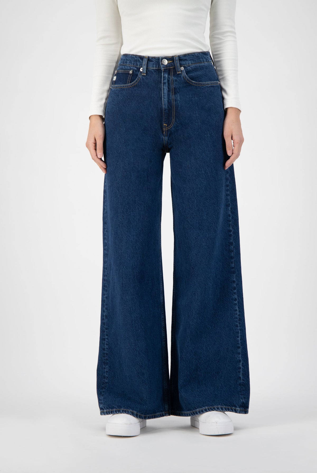 Wide-leg blue denim jeans with high waist paired with a fitted white knit top, showcasing a stylish modern fashion look.